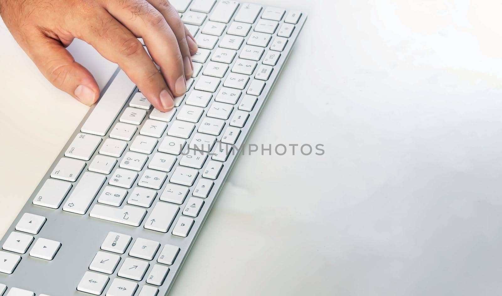 a male hand typing on a modern computer keyboard. Work and employment. Copy space. Wireless technology