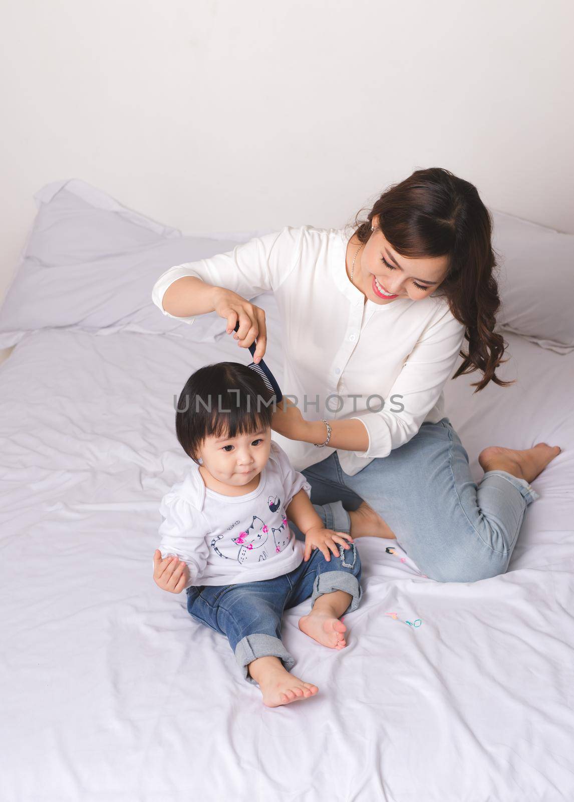 Happy loving family. Mom and child girl are having fun on the bed.