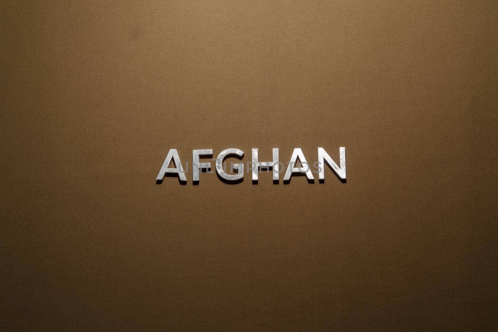 the word afghan laid with silver metal letters on rough tan khaki canvas fabric by z1b