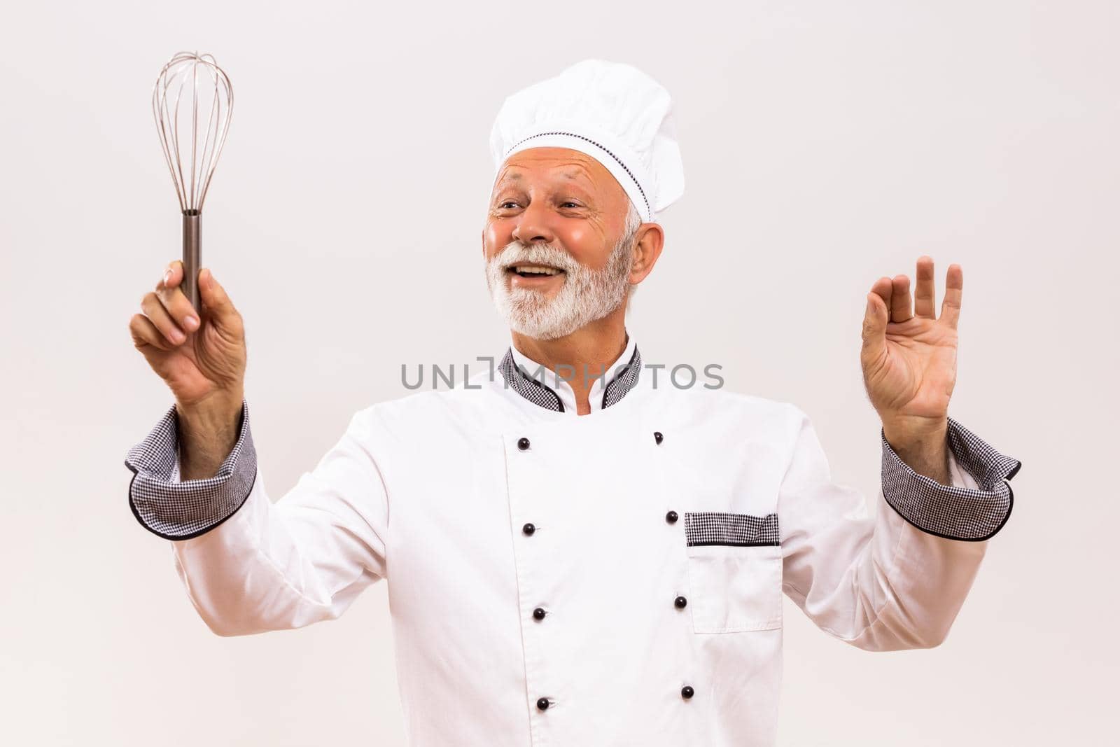 Image of  musical conductor senior chef with wire whisk on gray background.