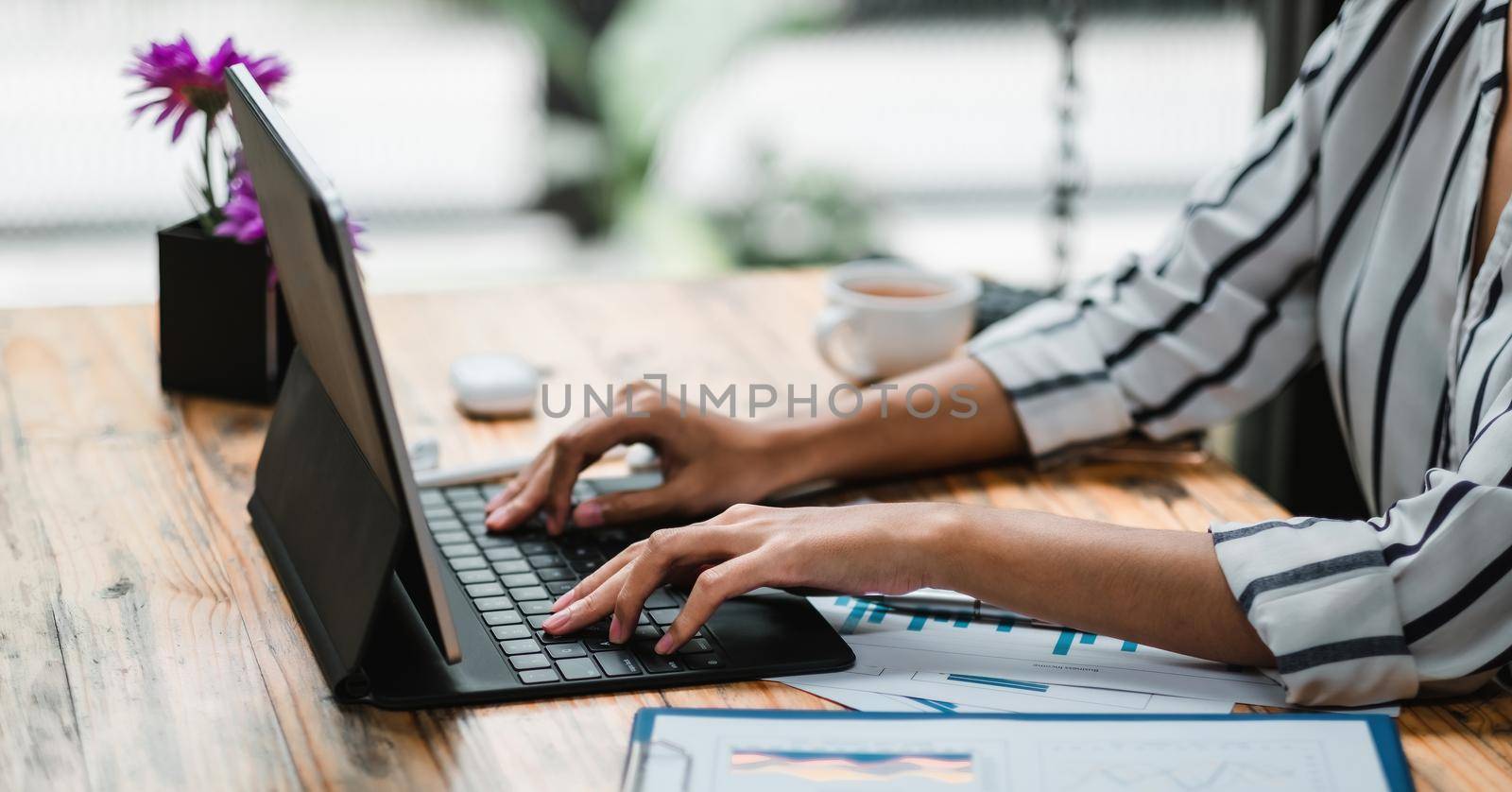 Close up of student girl hands comparing notes on digital tablet sitting on a desk. female using tablet at cafe. business finance concept. by nateemee