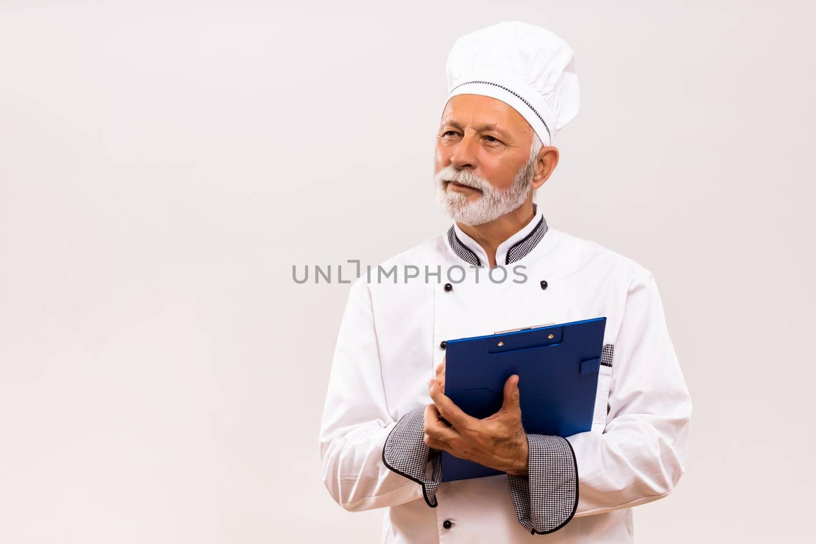 Senior  chef holding cookbook by Bazdar