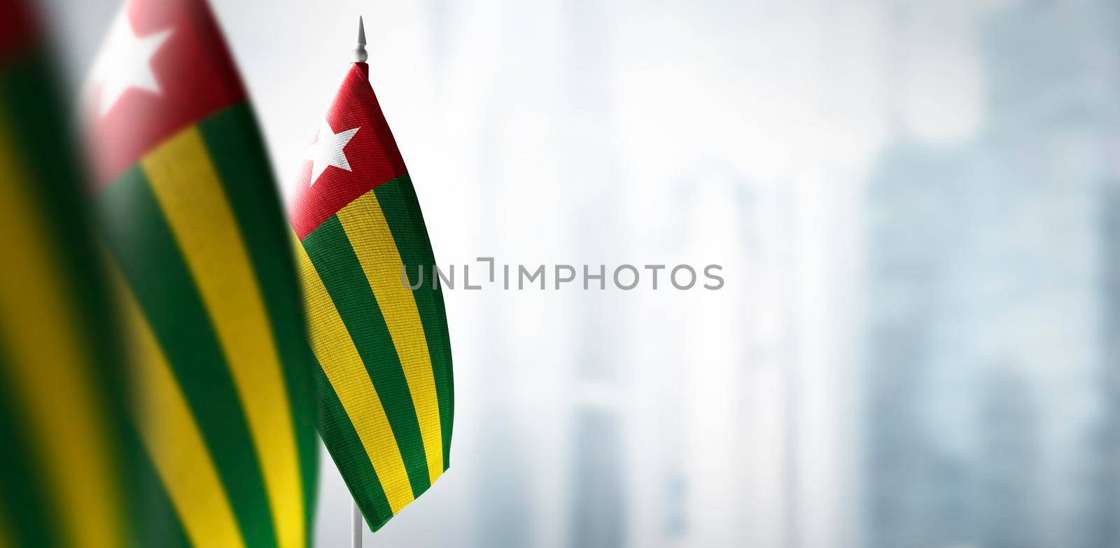 Small flags of Togo on a blurry background of the city by butenkow