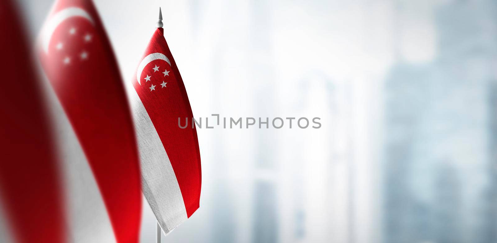 Small flags of Singapore on a blurry background of the city.