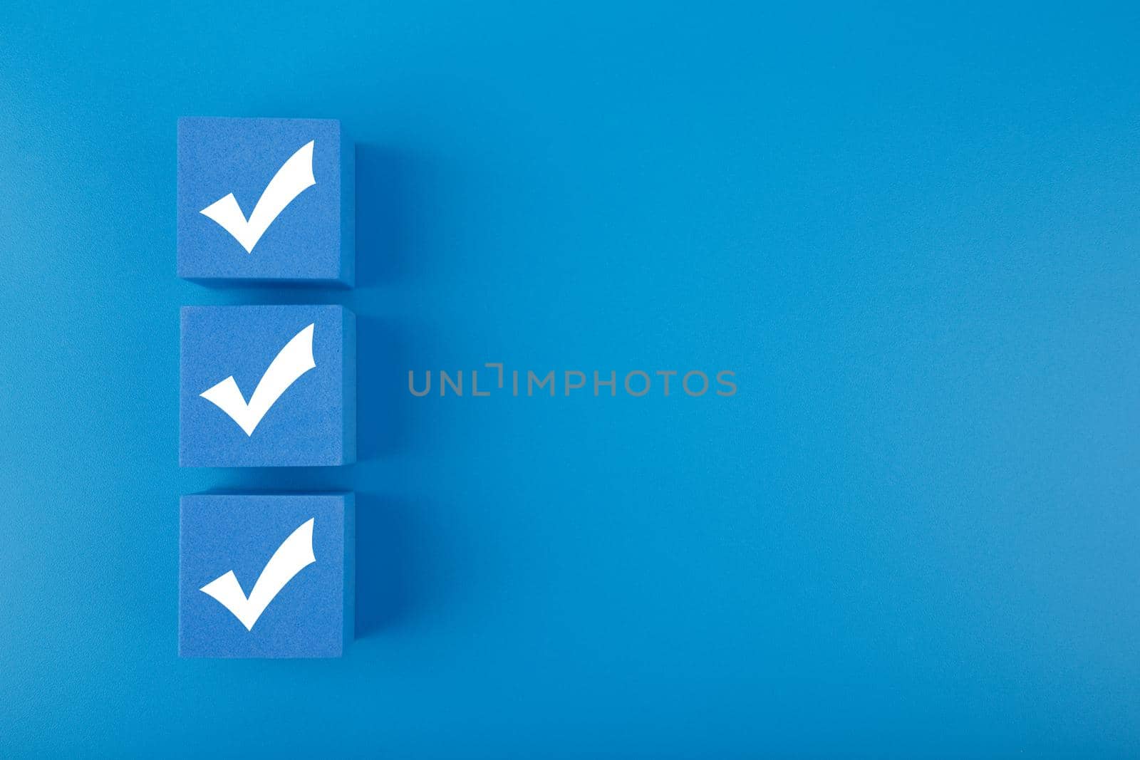 Three checkmarks on blue cubes against blue background with copy space by Senorina_Irina