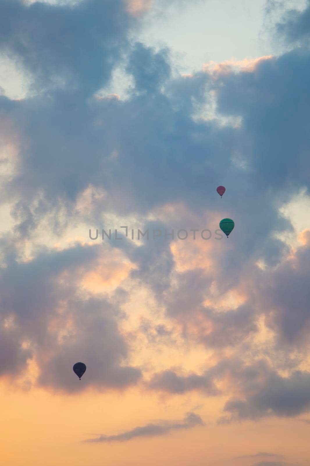 three hot air balloons in colorful sky with clouds by ahavelaar