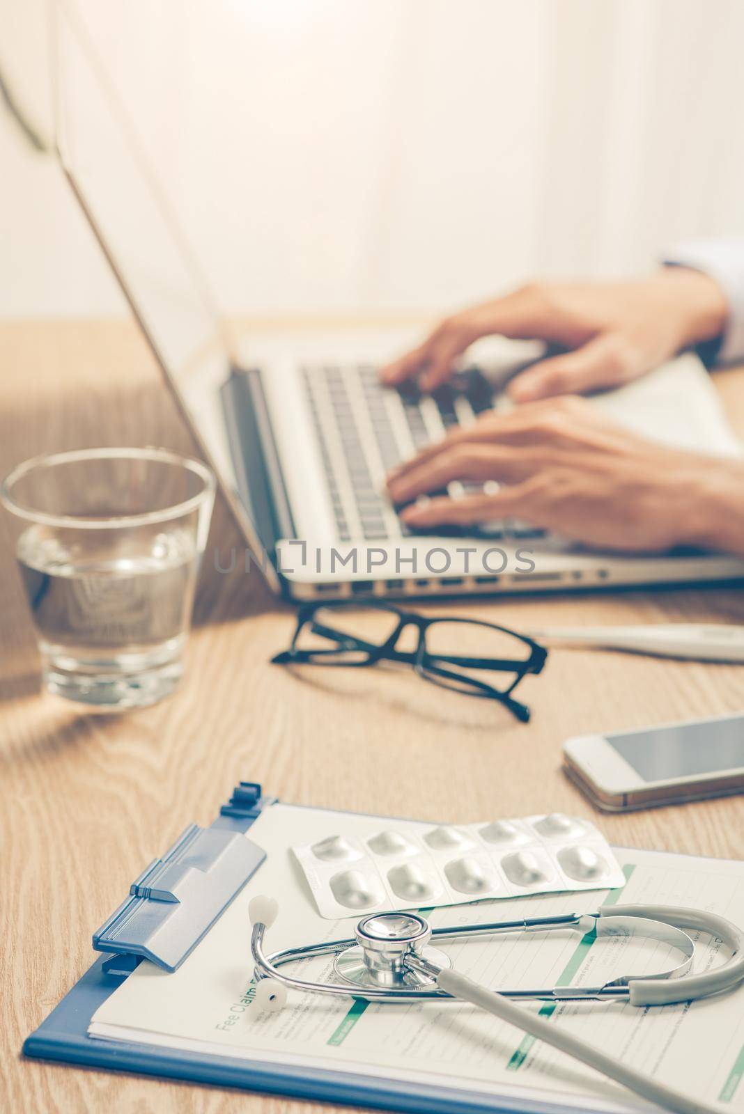 Male doctor working at wooden desk in clinic