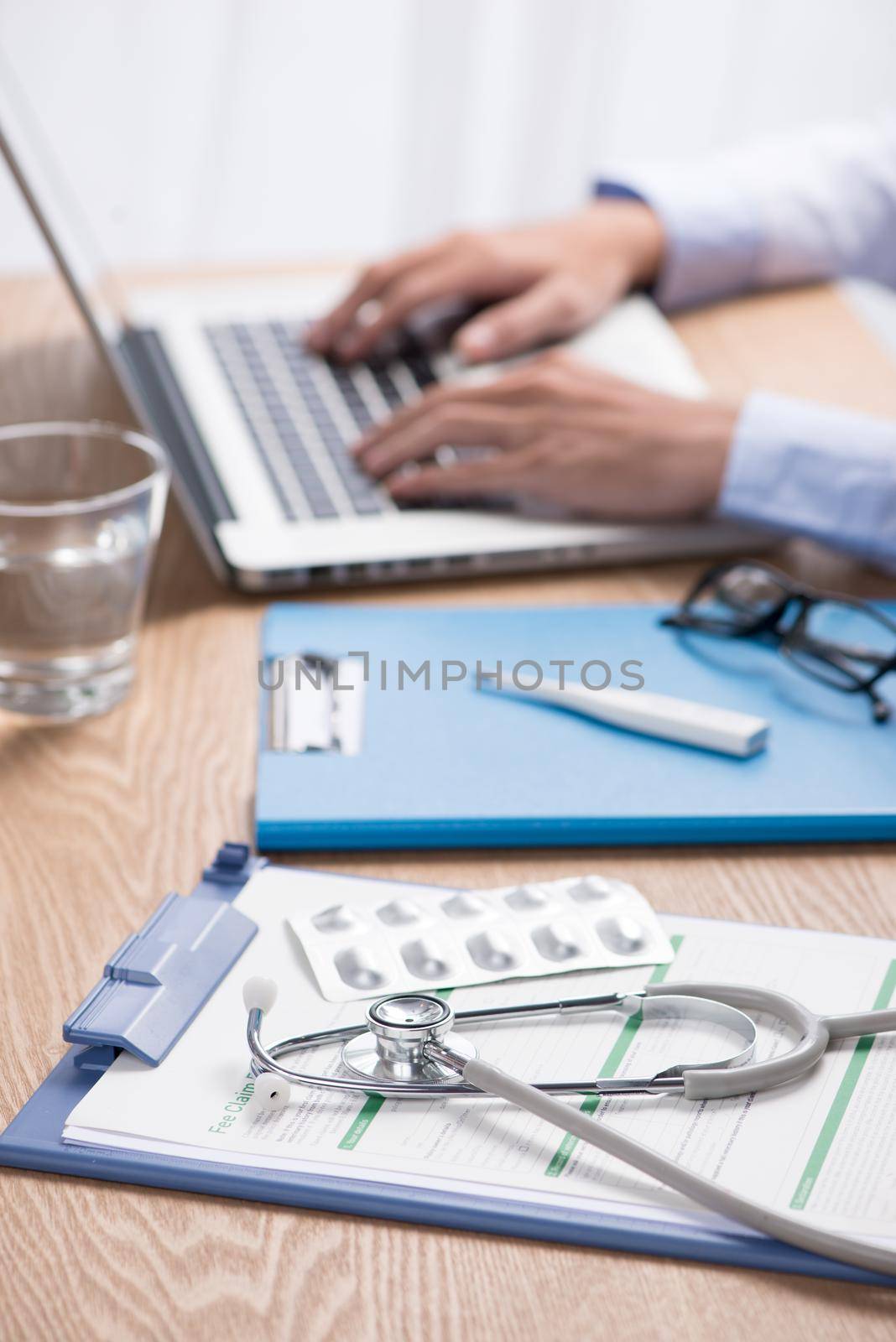 Male doctor working at wooden desk in clinic