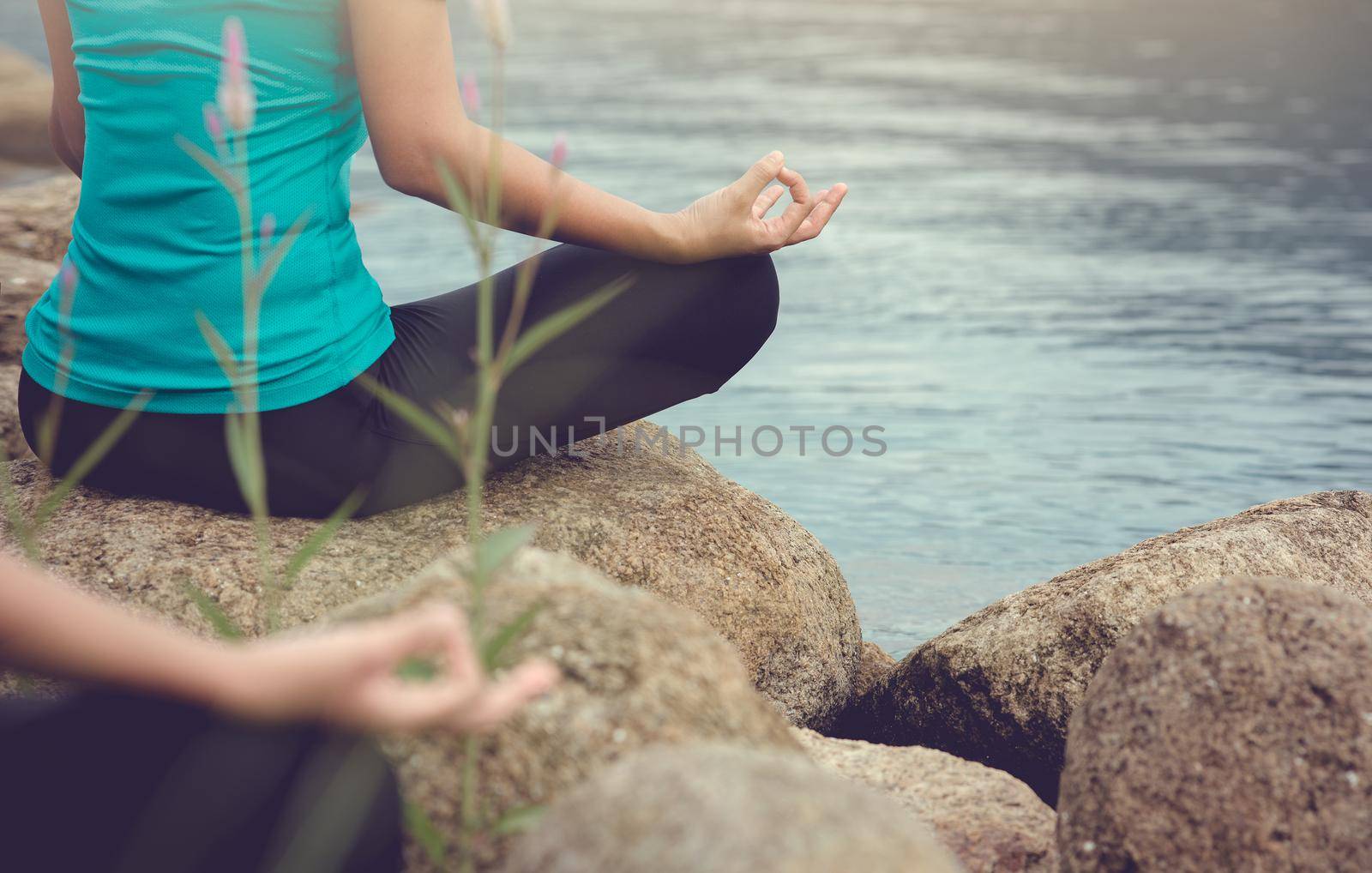 Young woman practicing yoga and meditate in the lotus pose outdoor beside the lake in the morning.