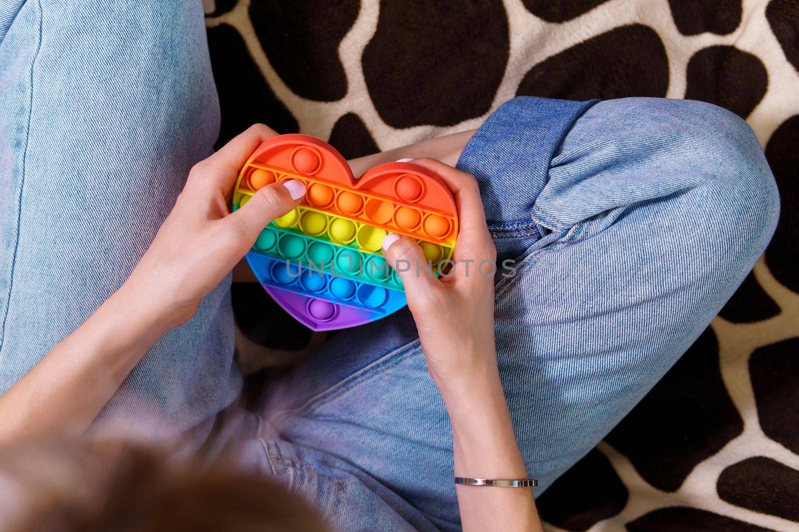 Girl plays with colorful rainbow pop it toy. Selective focus by darksoul72