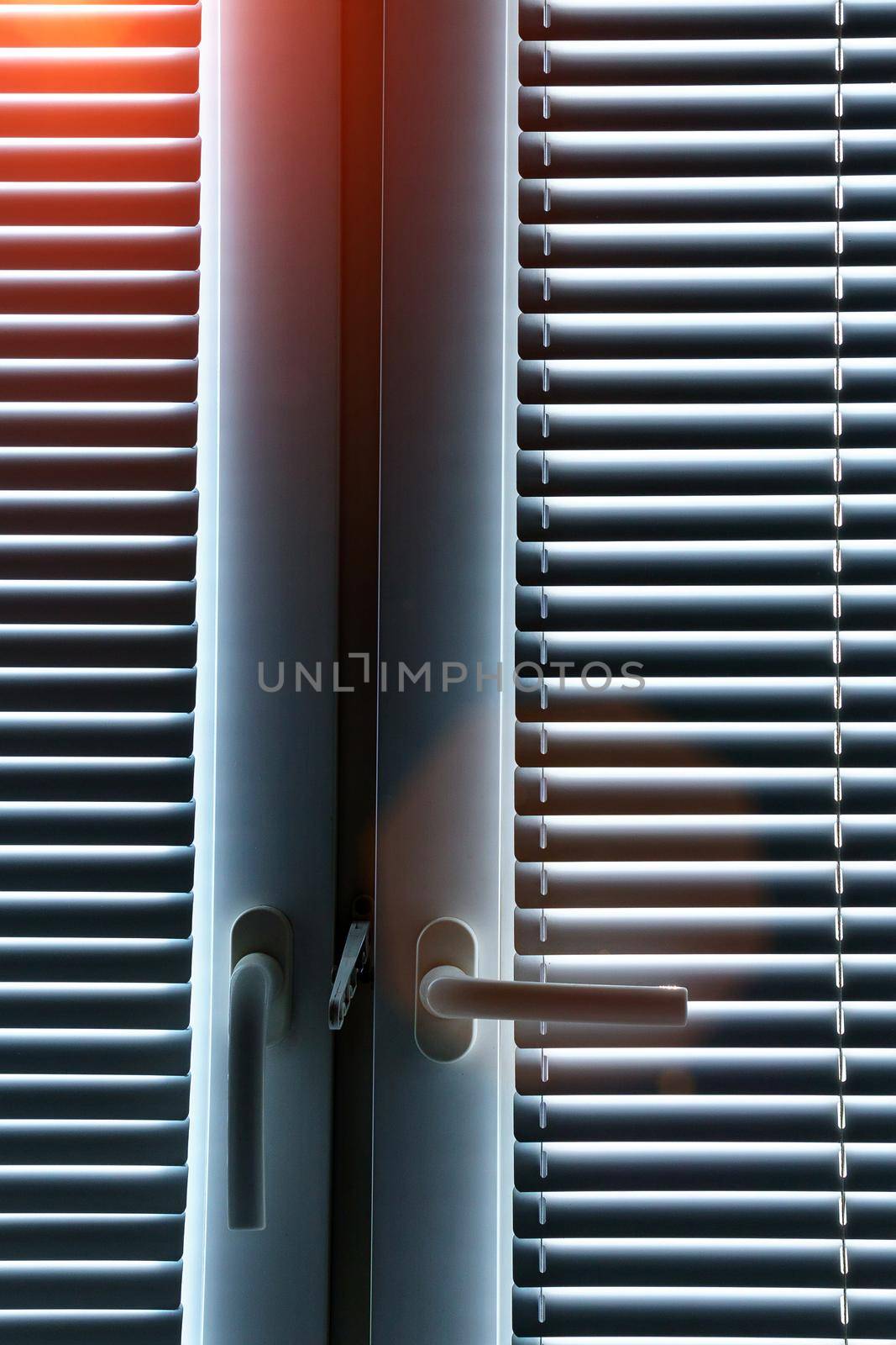 Aluminum blinds on the office windows. Made from metal. Modern sun protection and window decoration. Vertical photo