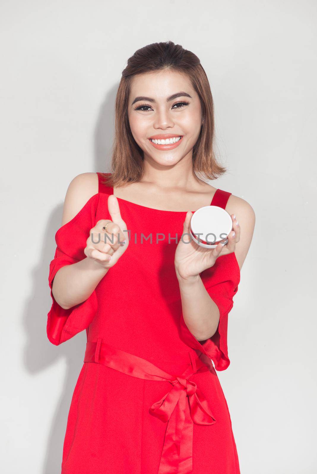 Fashion lifestyle portrait of young asian woman holding foundation cosmetic product 