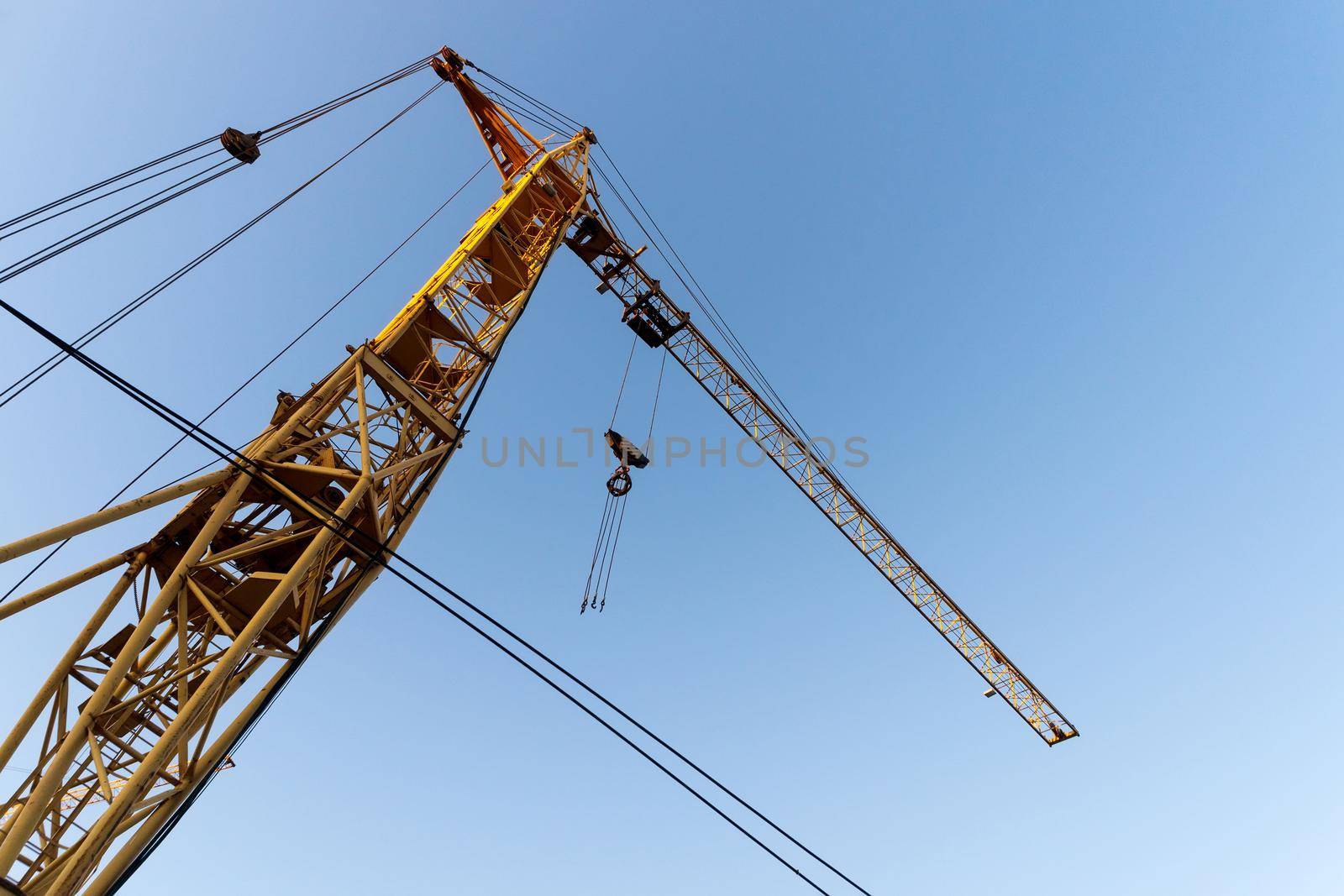 Construction crane. Huge crane against blue sky. Self-erection cranr. Tower crane.