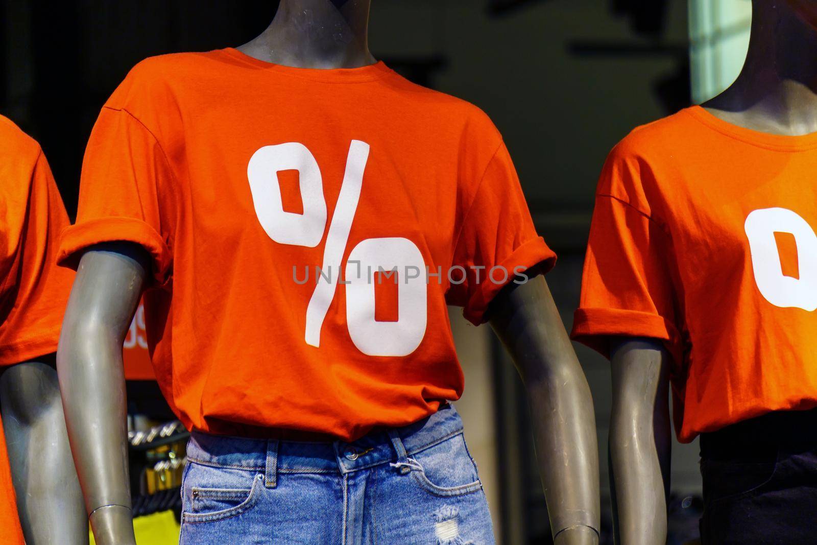 Dummies in store shop mall in red t-shirts with percent symbol sign. Sales discounts concept. Selective focus