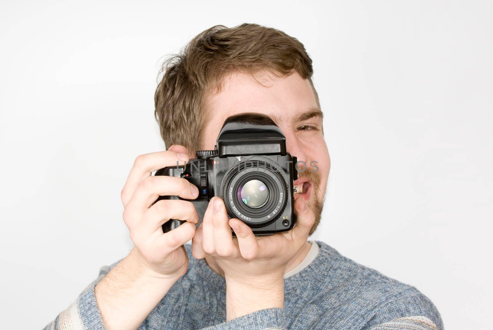 Young cheerful photographer with medium format camera shot against white background