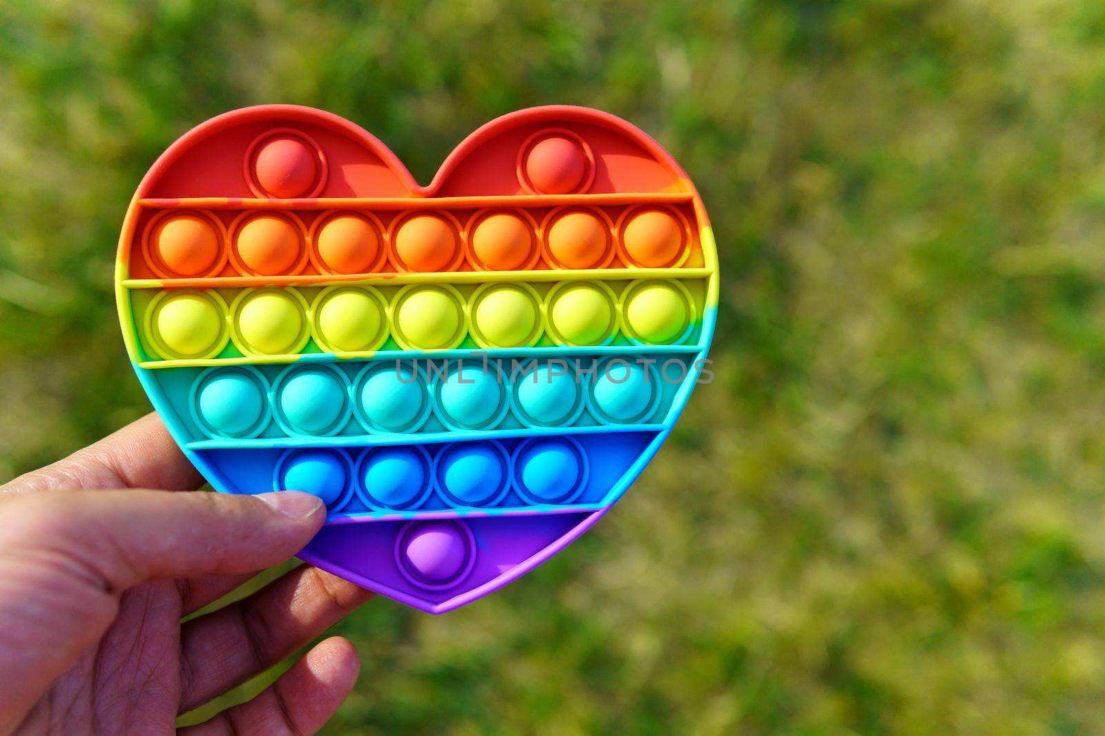 Colorful toy pop it in the form of a heart in the hand close-up by darksoul72