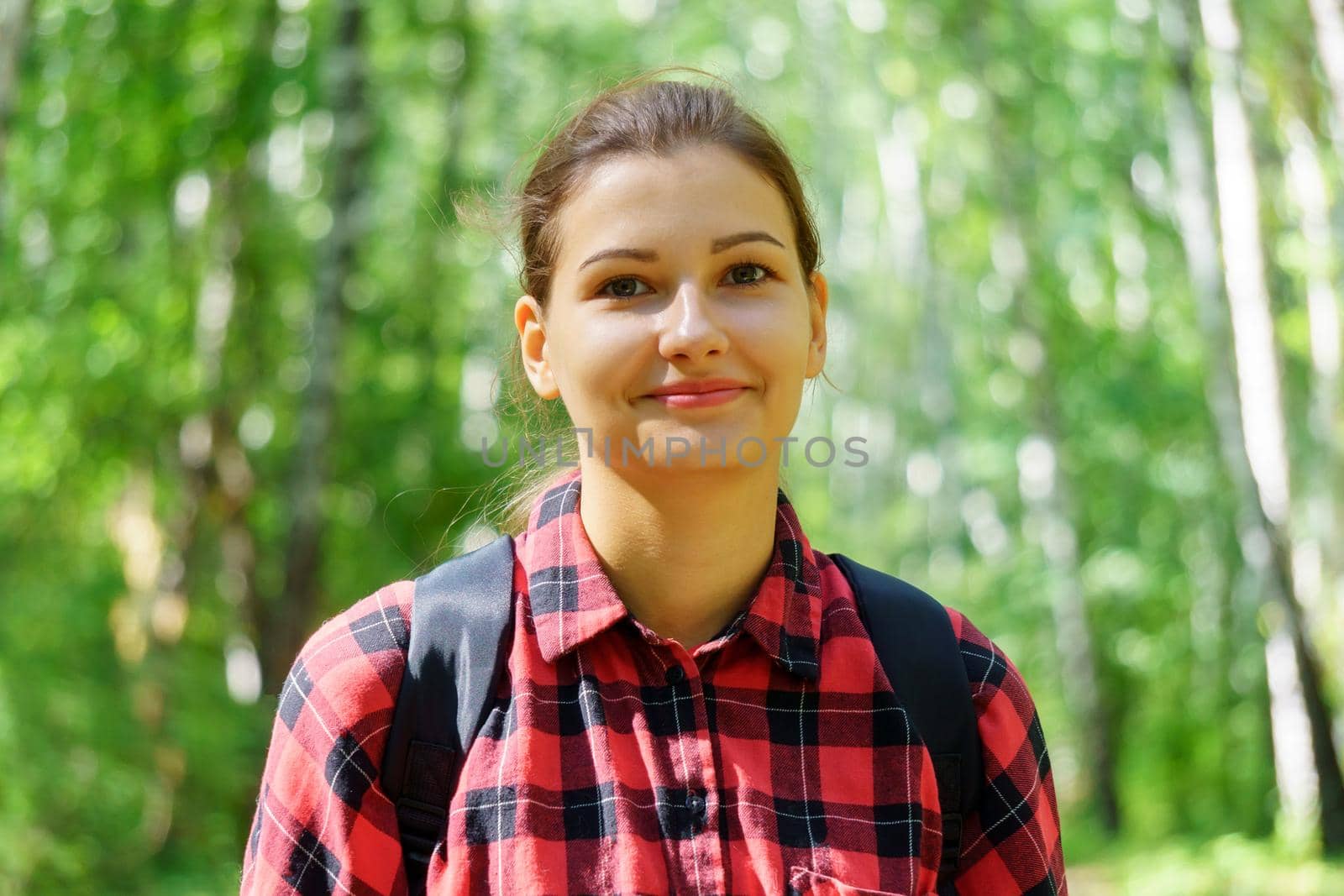 Portrait of a young girl in a red shirt on a green unfocused forest background. Selective focus by darksoul72