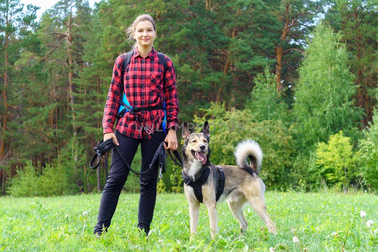 A young girl in a red shirt with her dog stands against the background of the forest. Walking with a pet by darksoul72