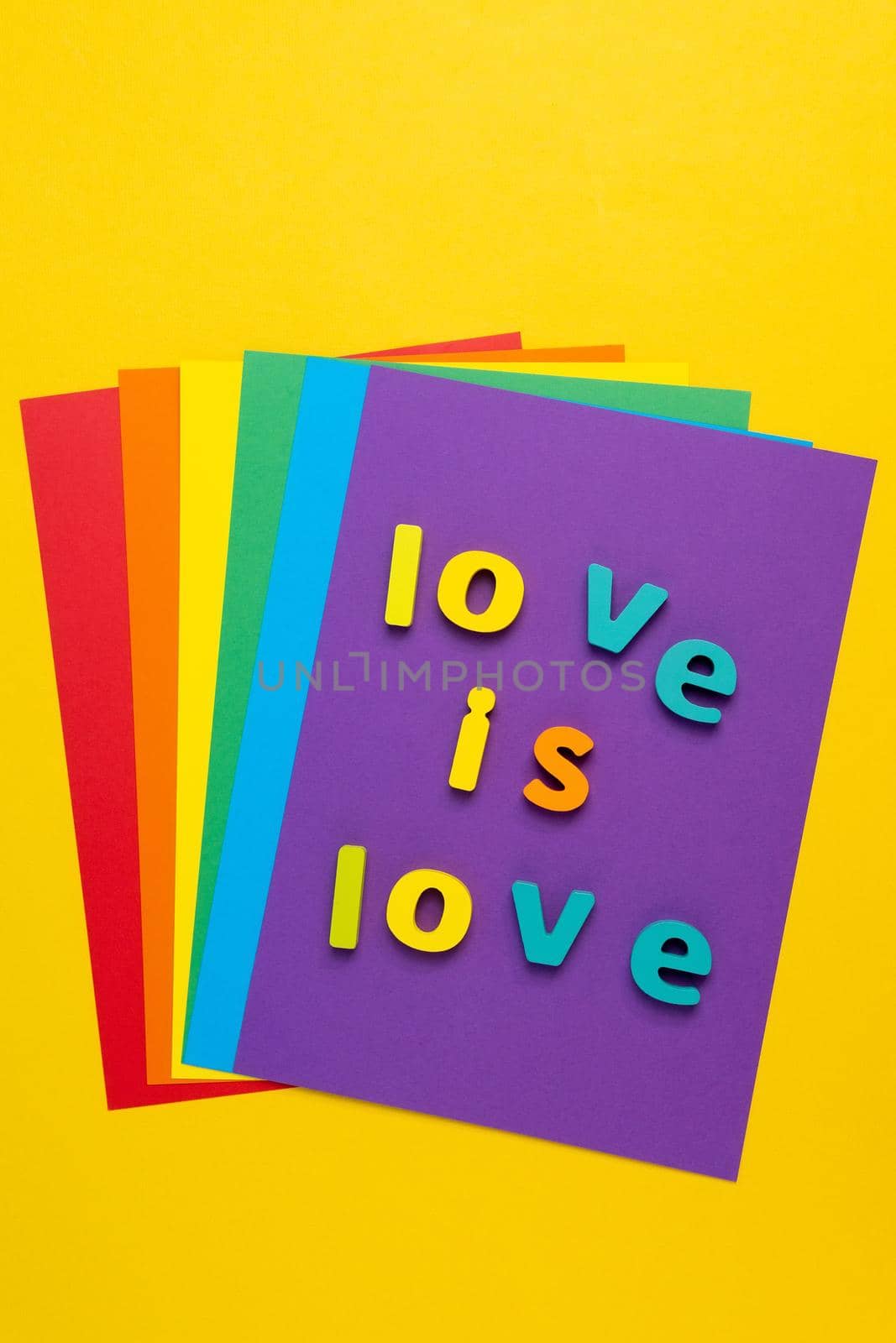 love is love on a yellow multicolored background. Symbol of tolerance on gay pride rainbow colors painted. Top view