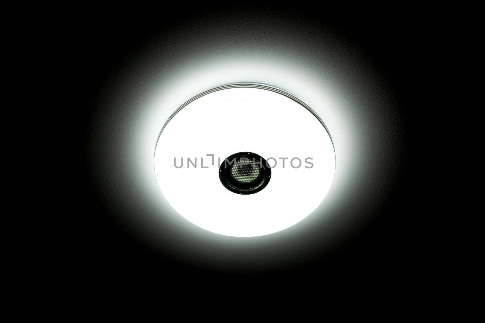 White light LED ceiling light with built-in wireless speakers over black background.