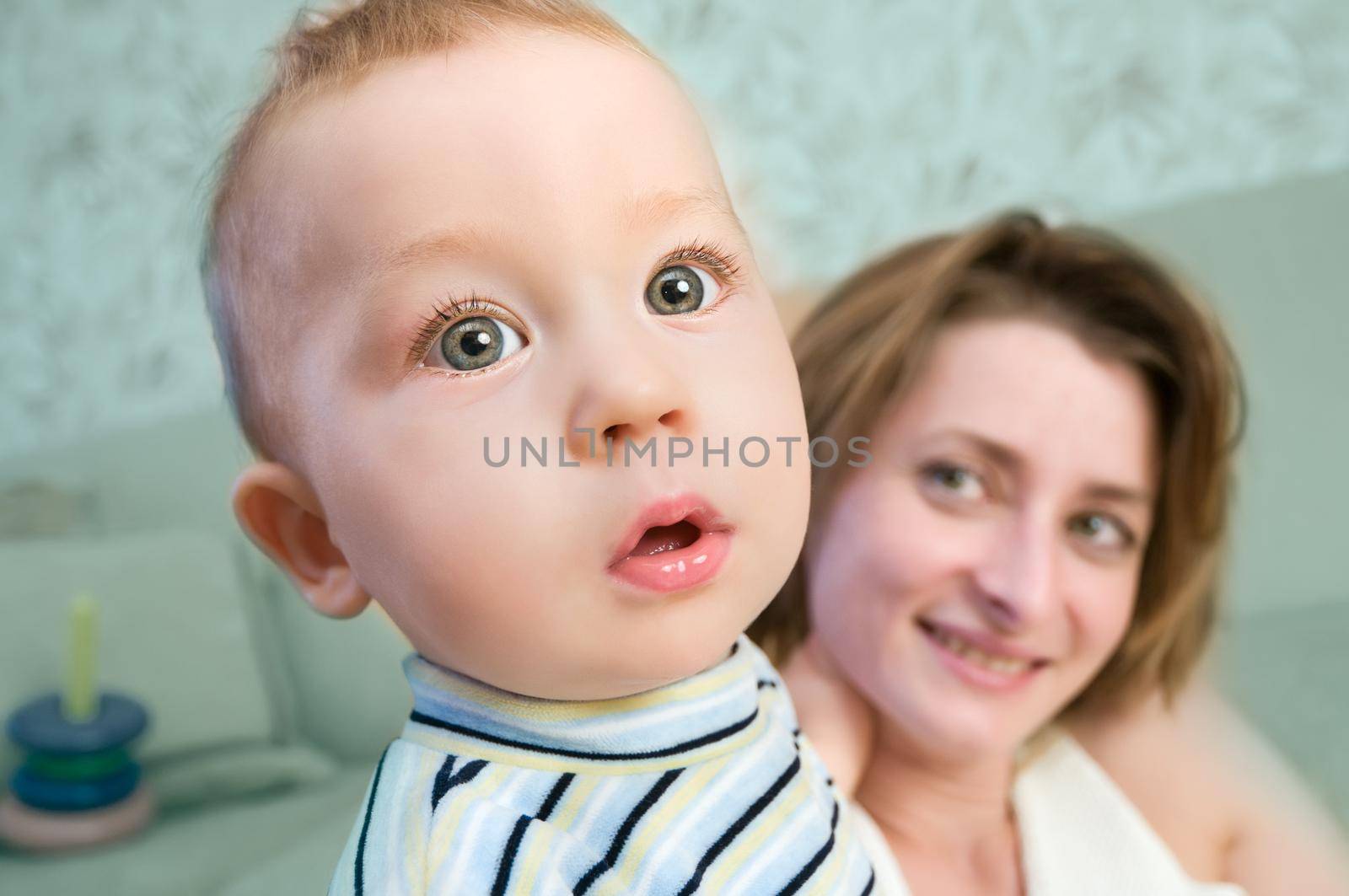 Closeup of a curious baby boy with his happy mother in the backgound