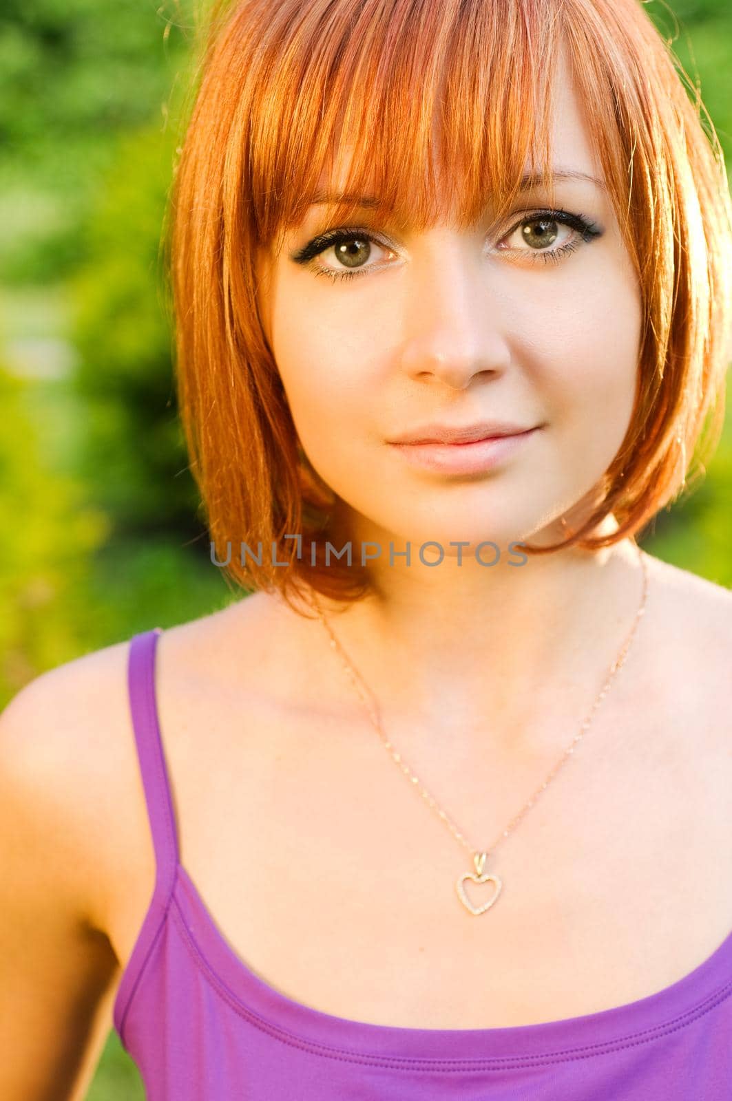 Beautiful healthy-looking red woman posing outdoors in a green park