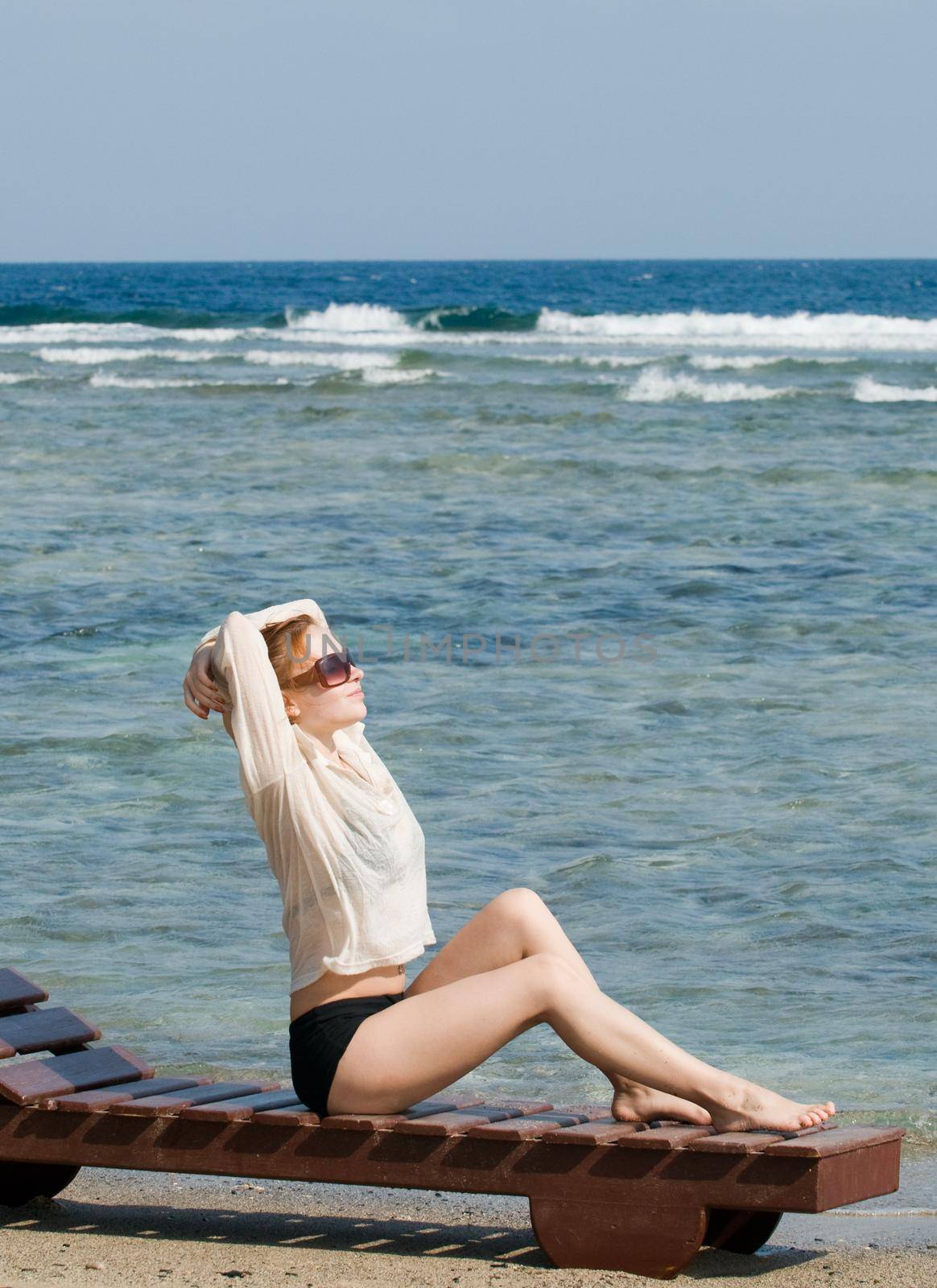 Beautiful red woman taking sun baths by the ocean