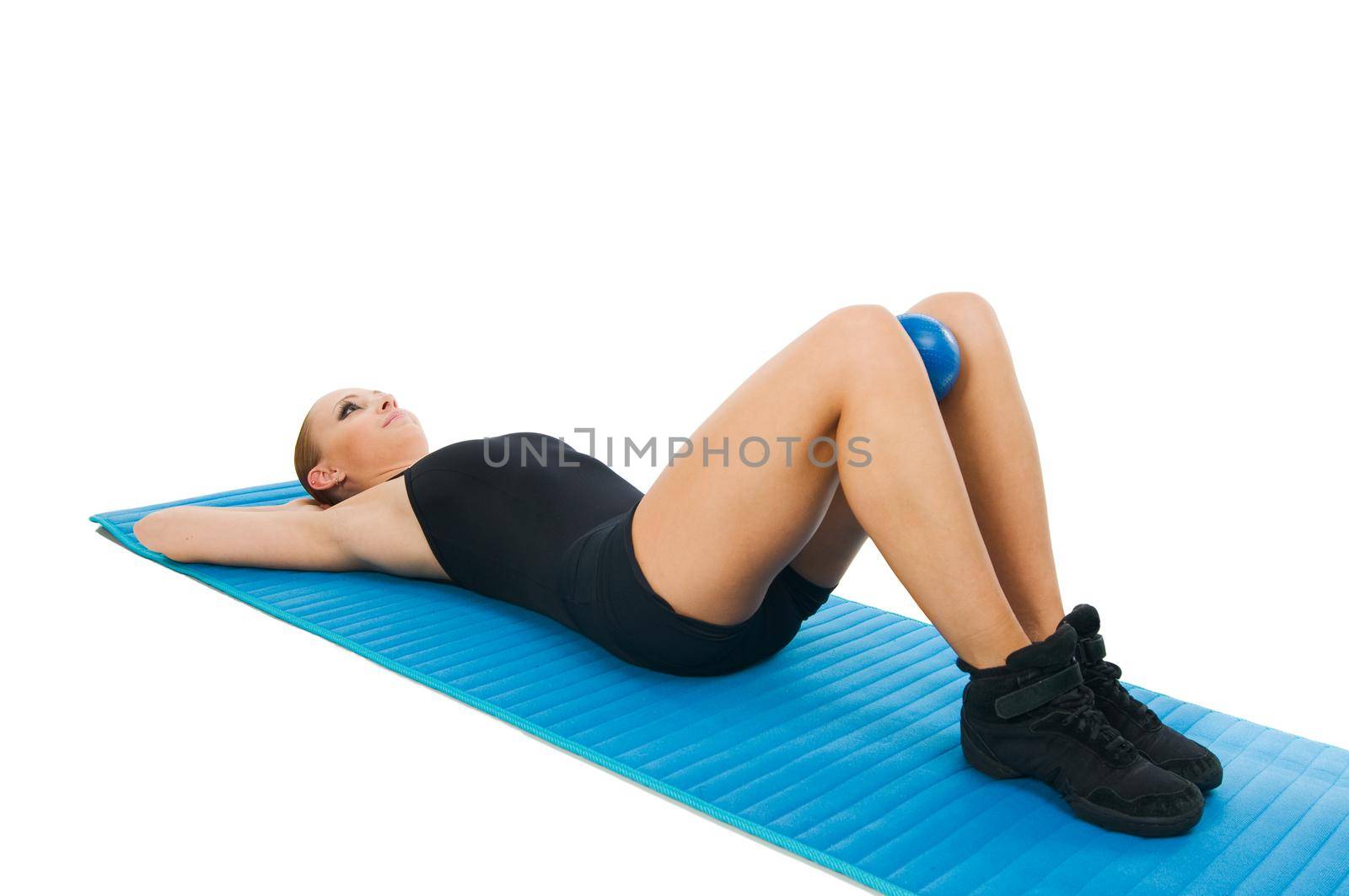 Beautiful fit red girl practicing pilates or callanetics with ball and blue yoga mat