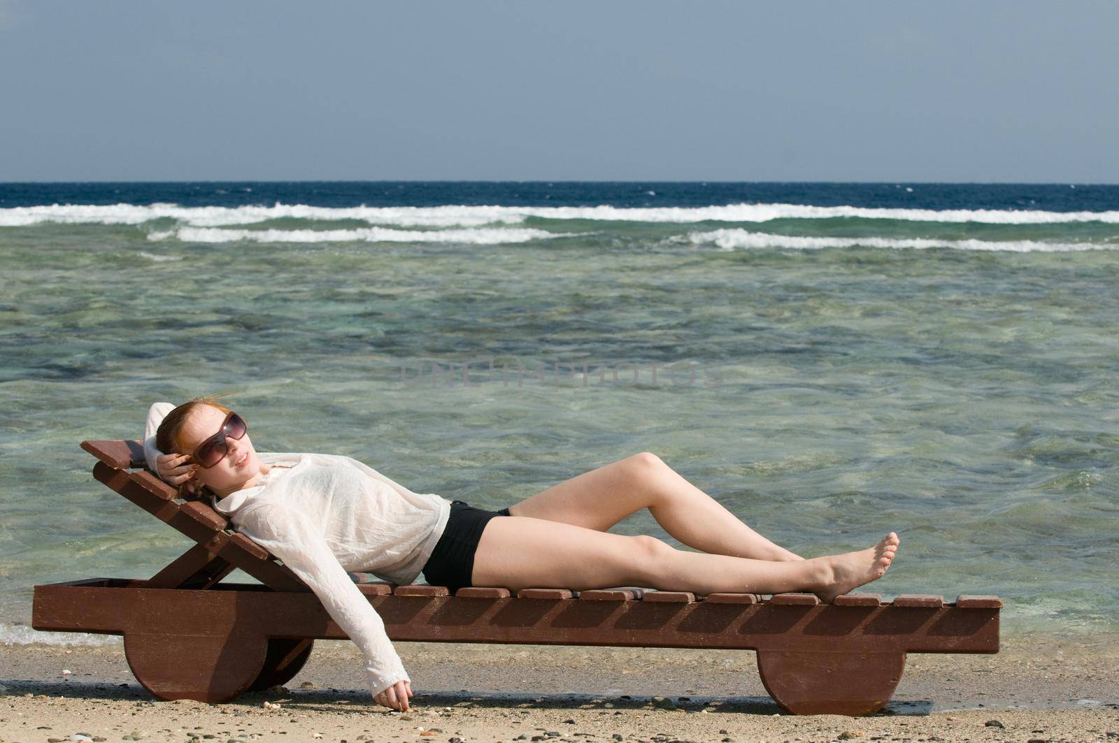 Beautiful red woman taking sun baths by the ocean