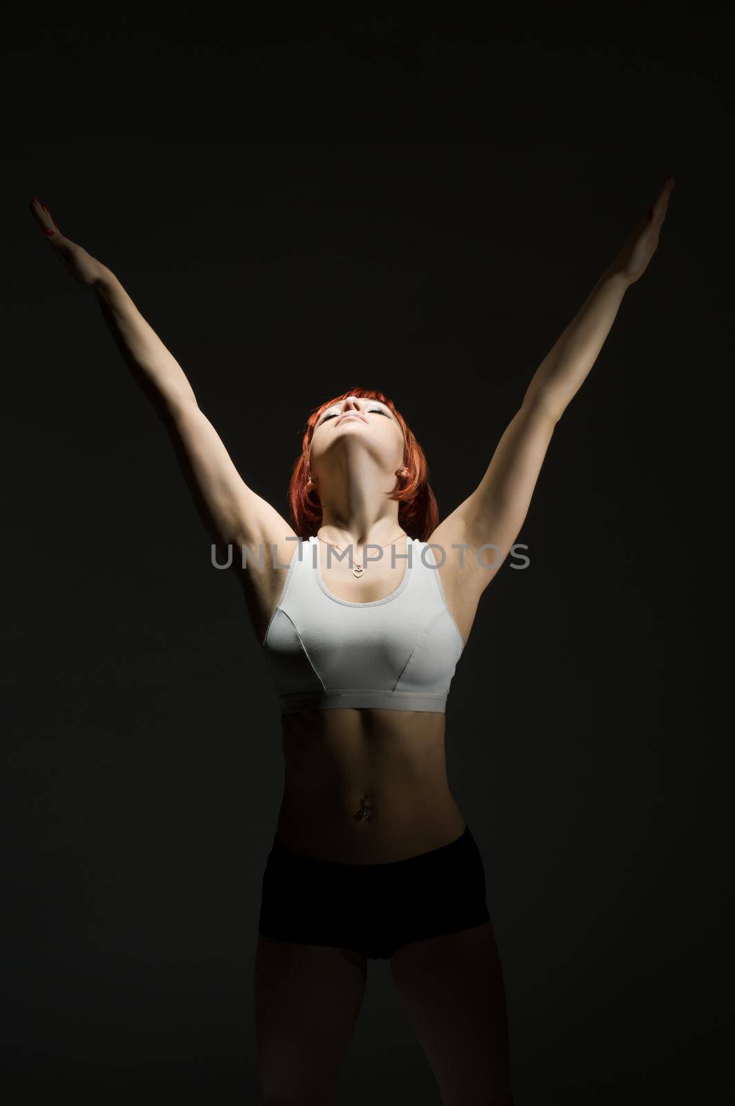 Fit red woman performing static power exercise in the spotlight