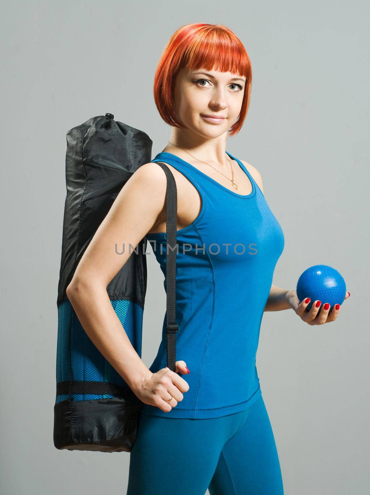 Red-haired fitness girl with yoga mat at the gym