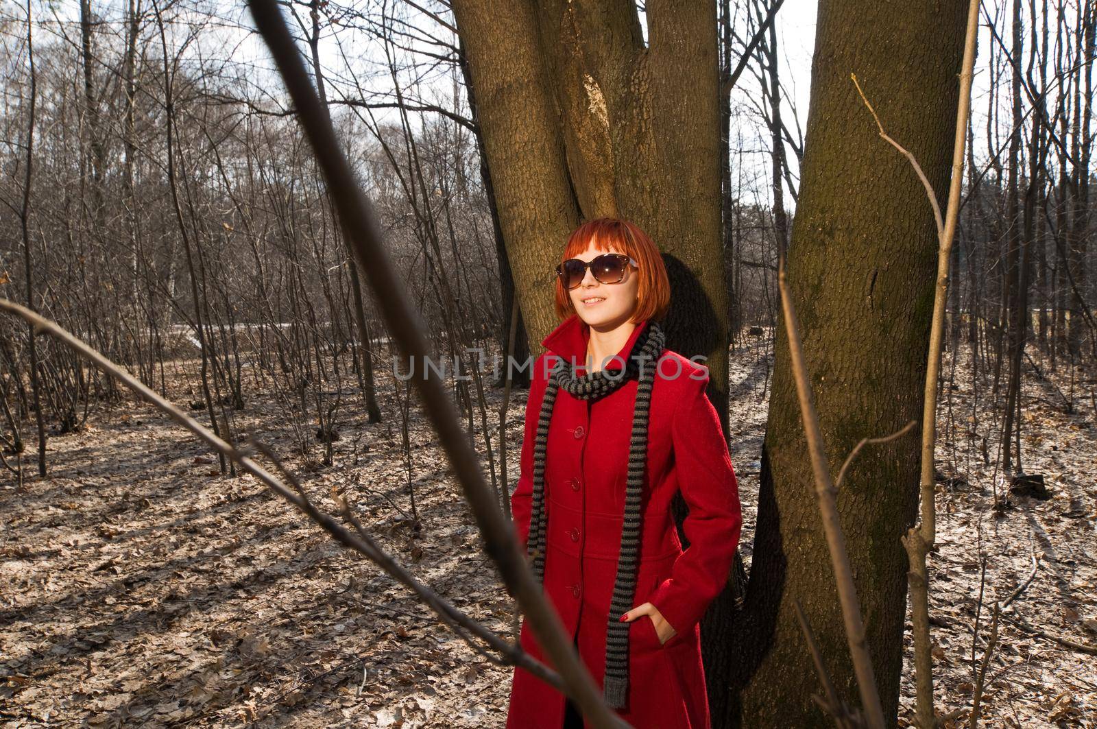 Beautiful girl wearing red coat and boots walking in the early spring