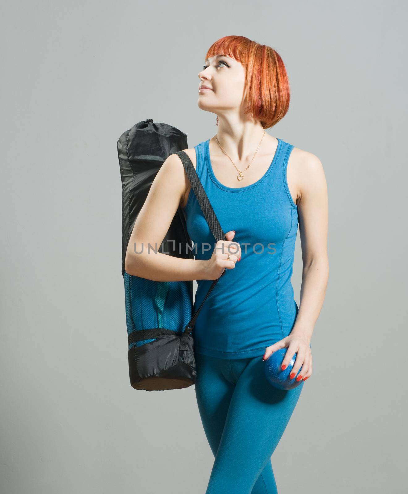 Red-haired fitness girl with yoga mat by nikitabuida