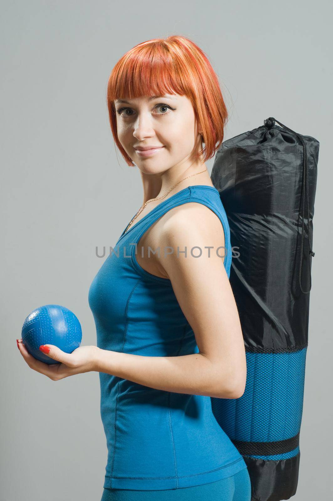 Red-haired fitness girl with yoga mat at the gym