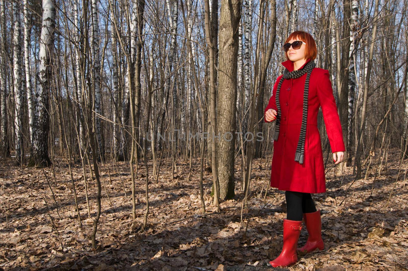 Beautiful girl wearing red coat and boots walking in the early spring