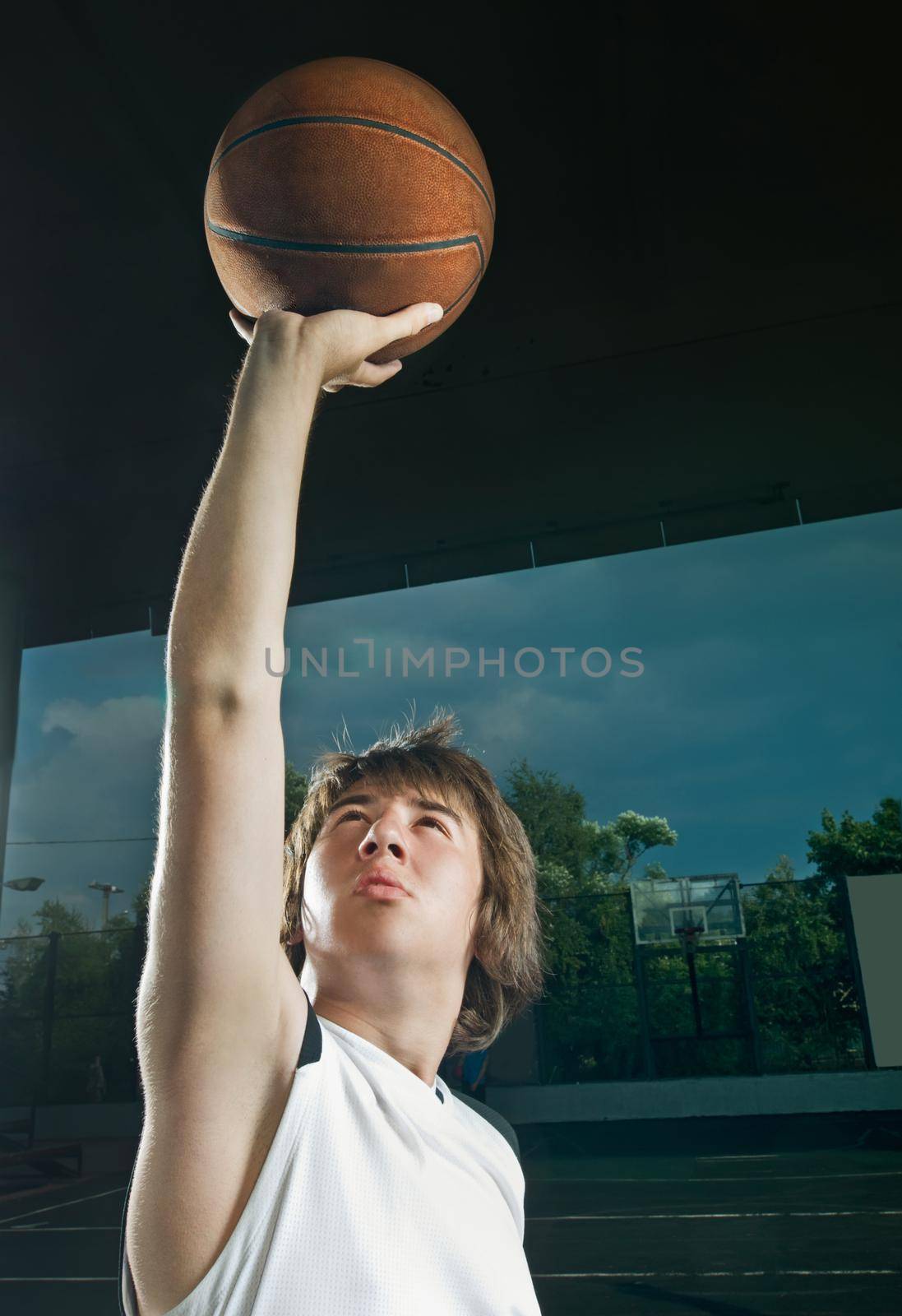 Teenage basketball player shooting the ball with outstretched hand