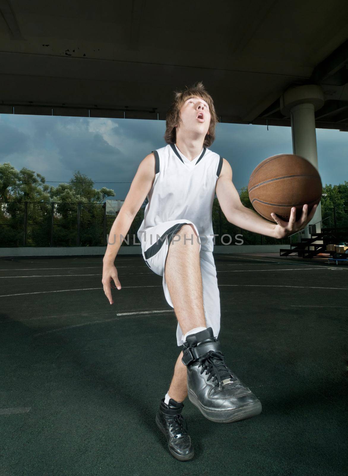 Teenager with basketball at the street playground