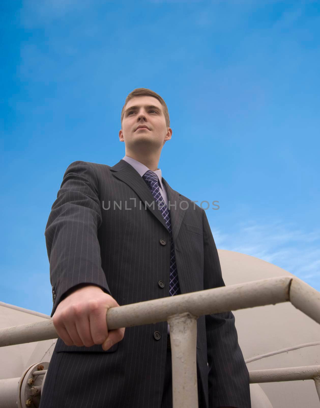 Young confident businessman looking ahead with industrial background