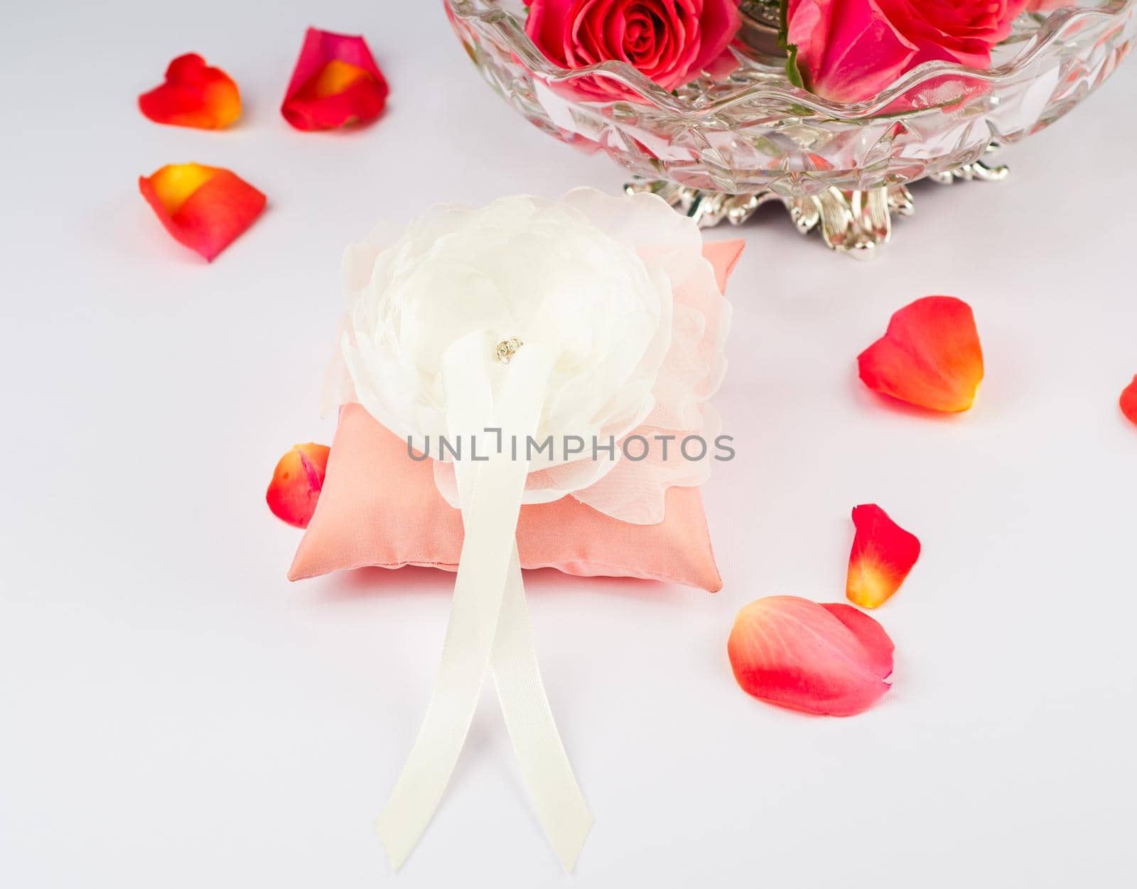 Exquisite pillow for wedding rings on gray background with rose petals