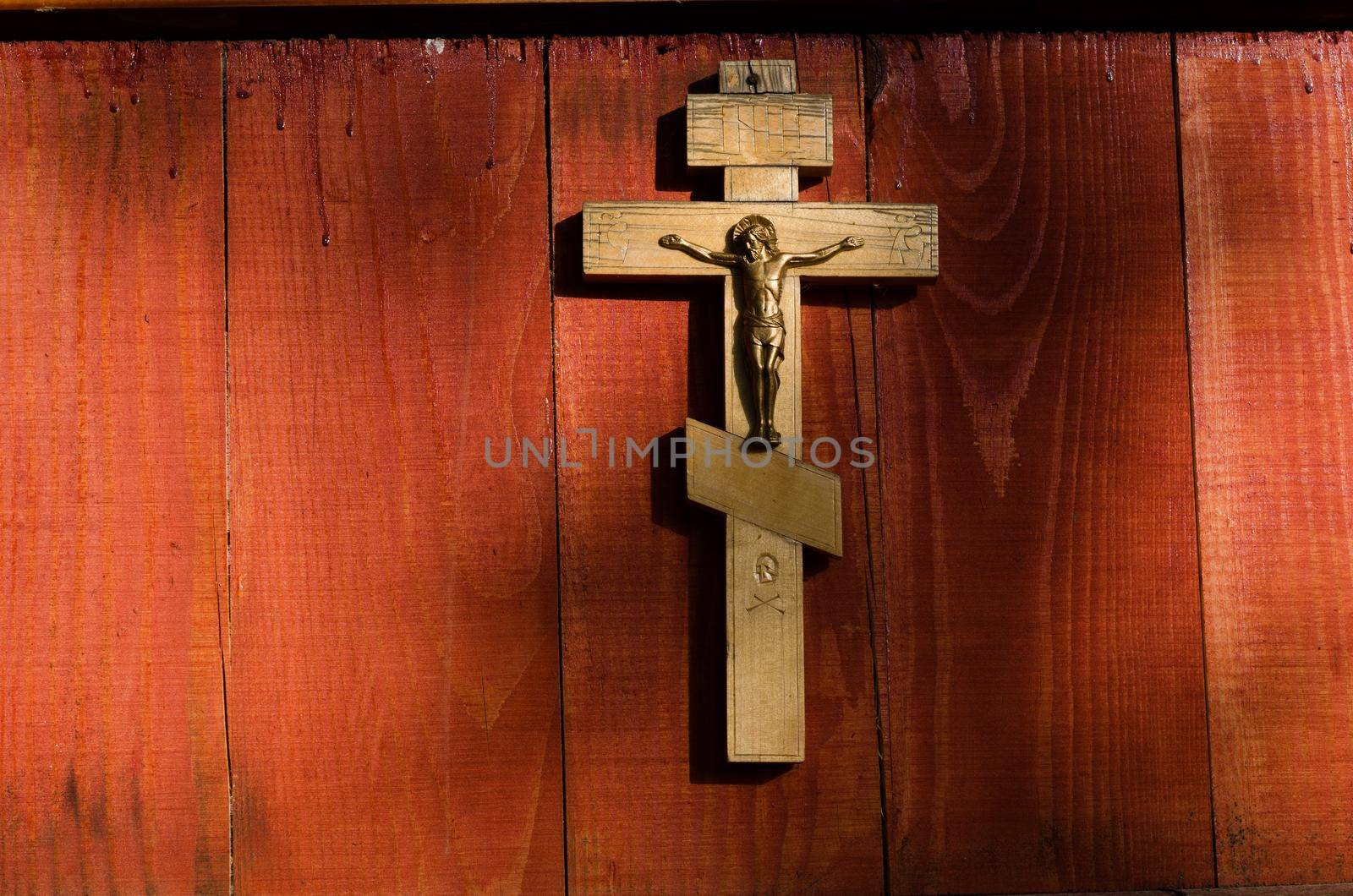 Small wooden crucifix hanging on wooden wall under beam of light