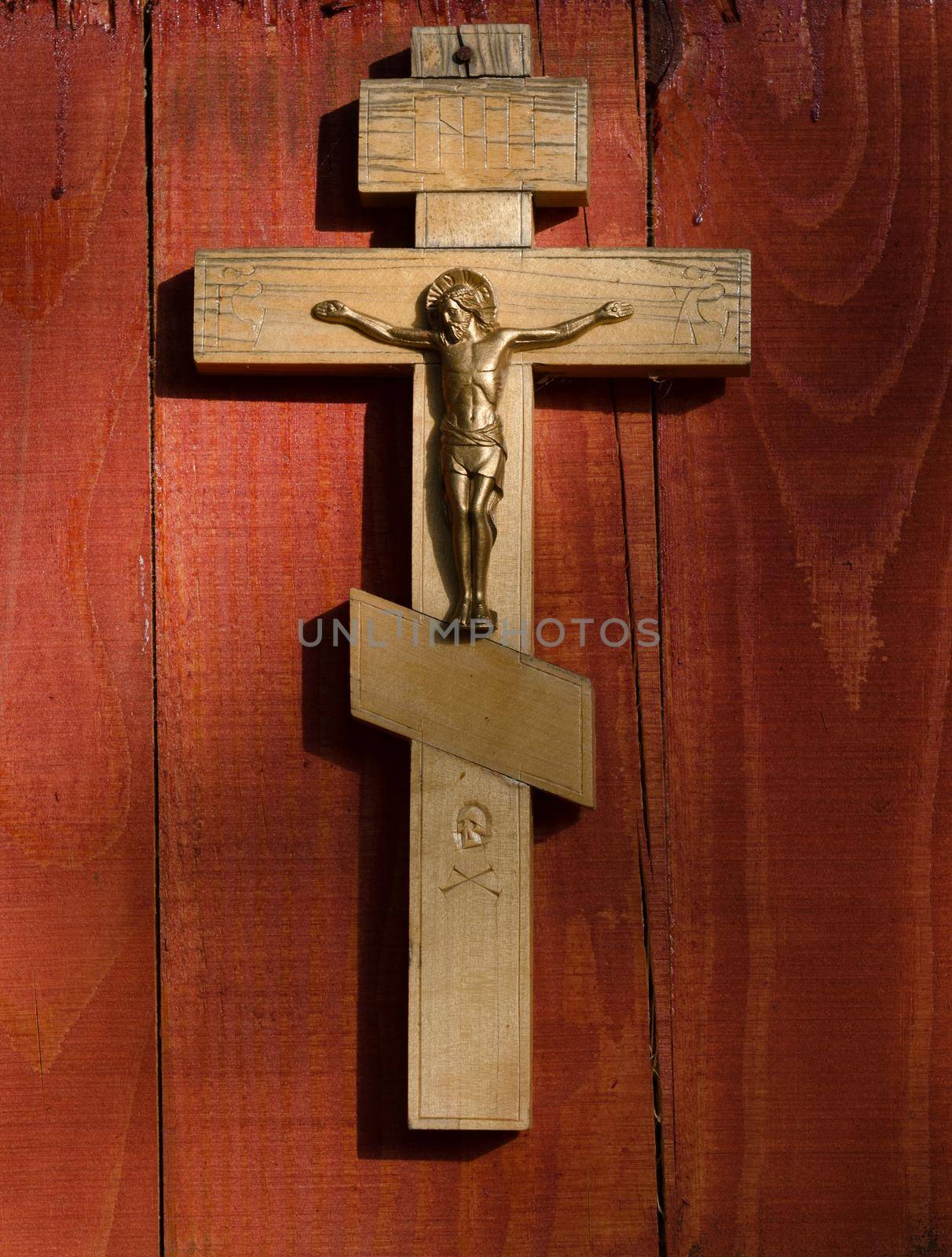 Small wooden crucifix hanging on wooden wall under beam of light