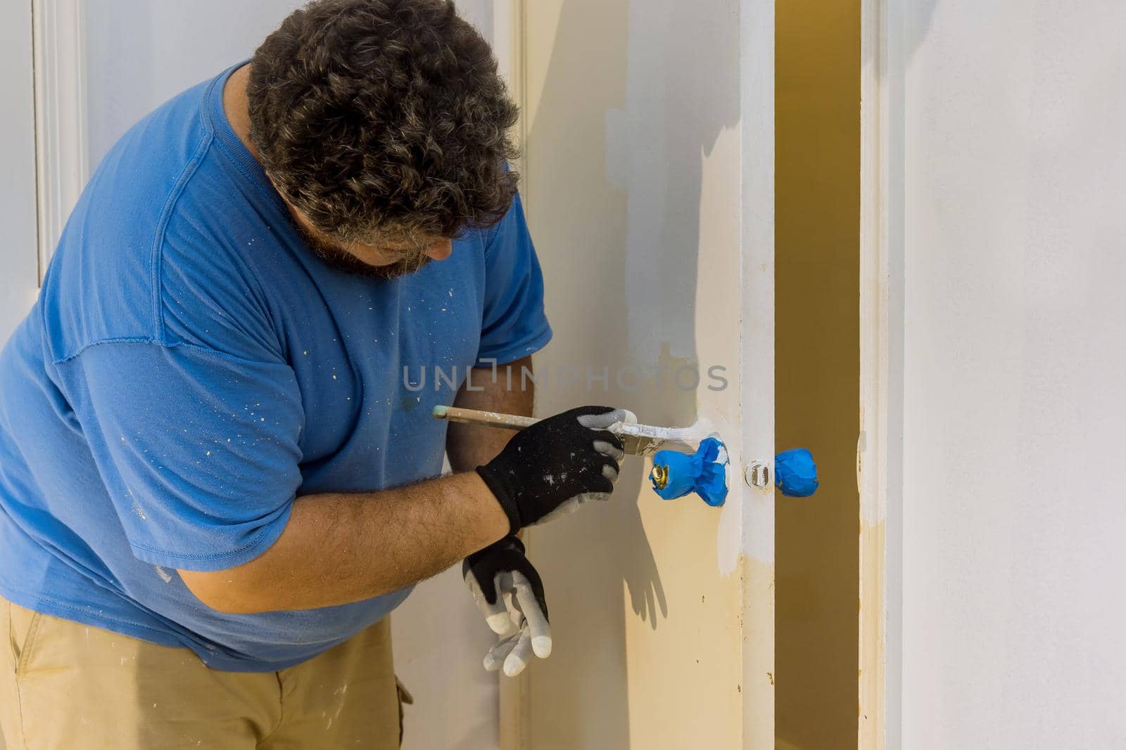Contractor master processes painter painting wooden doors with using paintbrush in a house