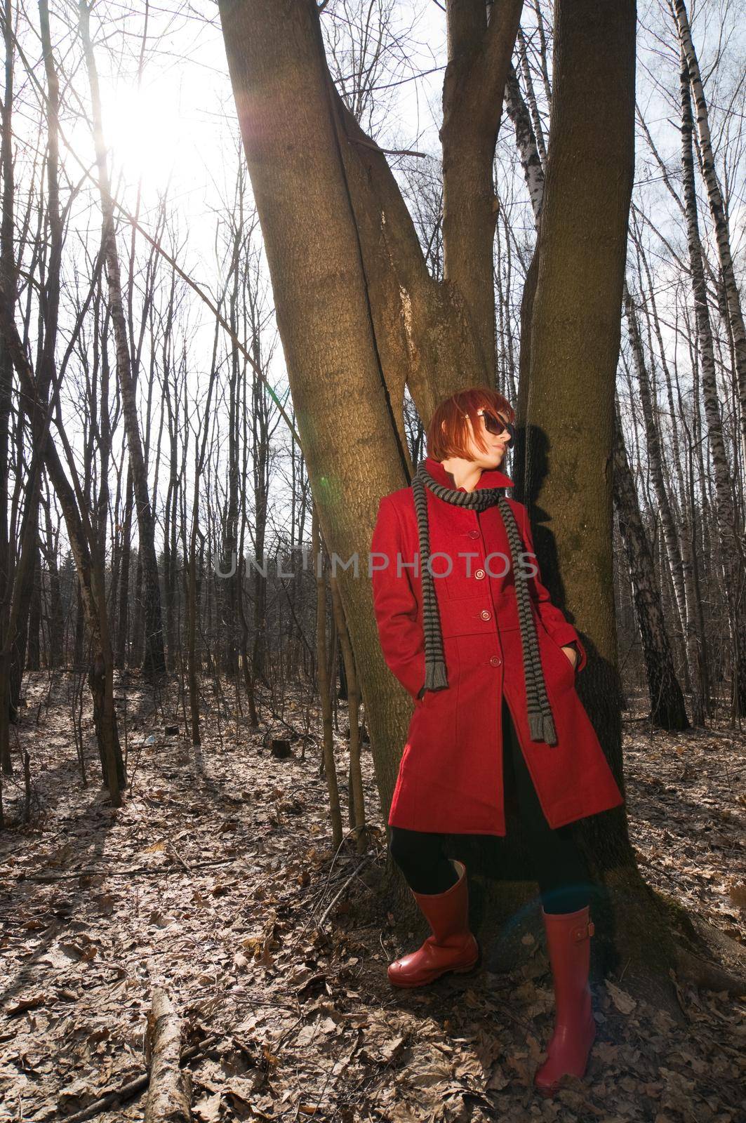 Beautiful girl wearing red coat and boots walking in the early spring