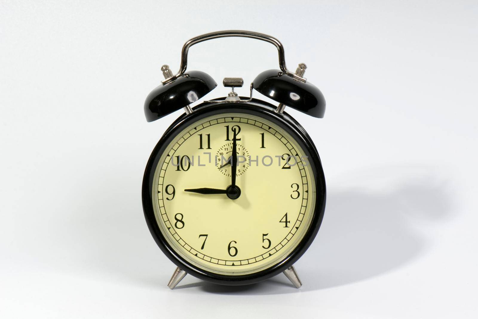 Old fashioned alarm clock showing 9 o'clock on a white background