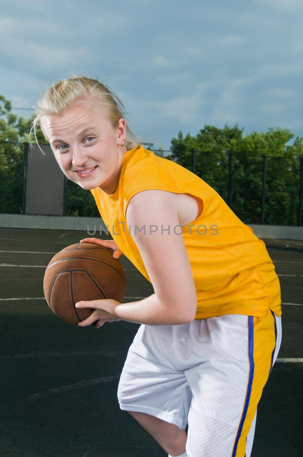 Teenage girl with basketball at streetball playground smiling