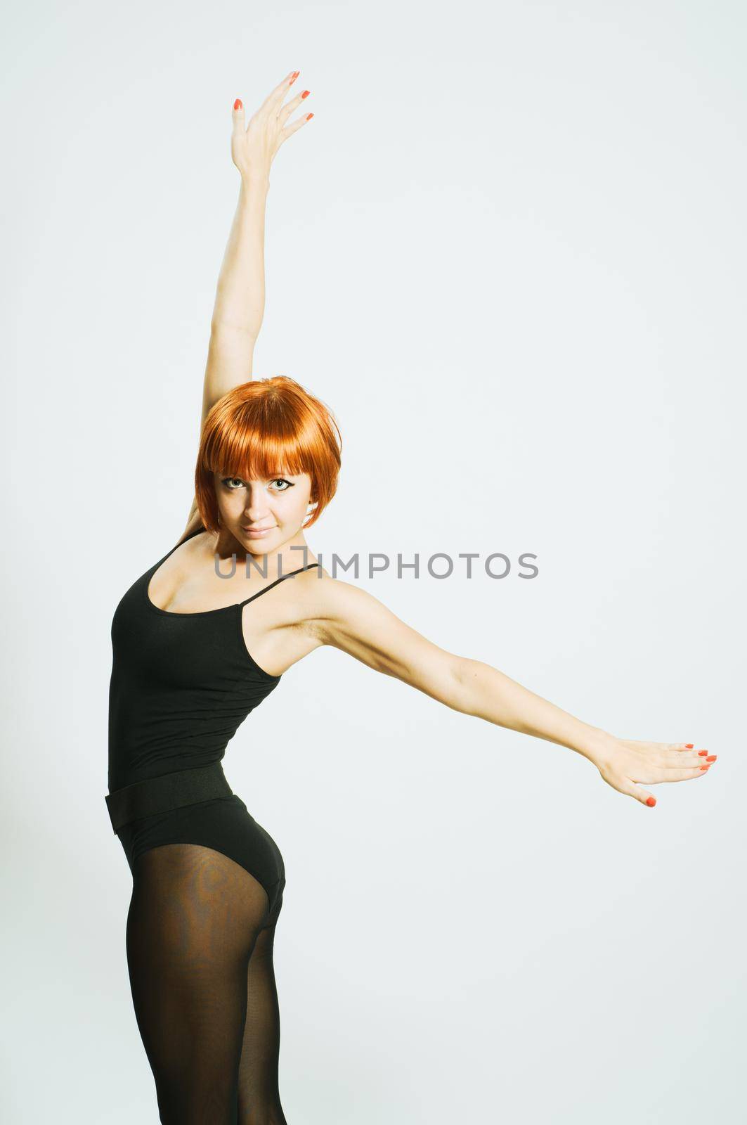 Beautiful red dancer wearing swimsuit with outstretched hands on white
