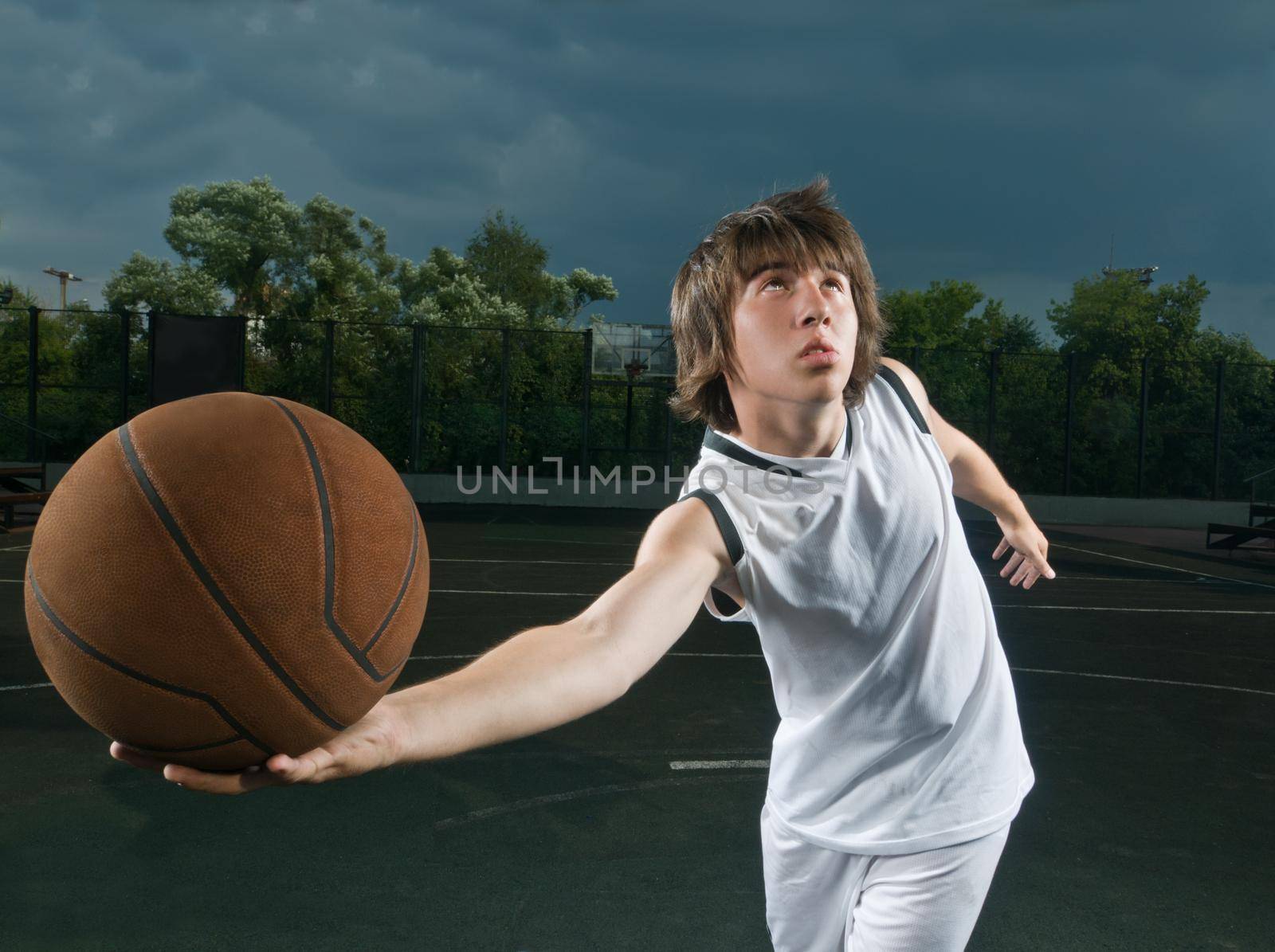 Teenager playing basketball at the street playground