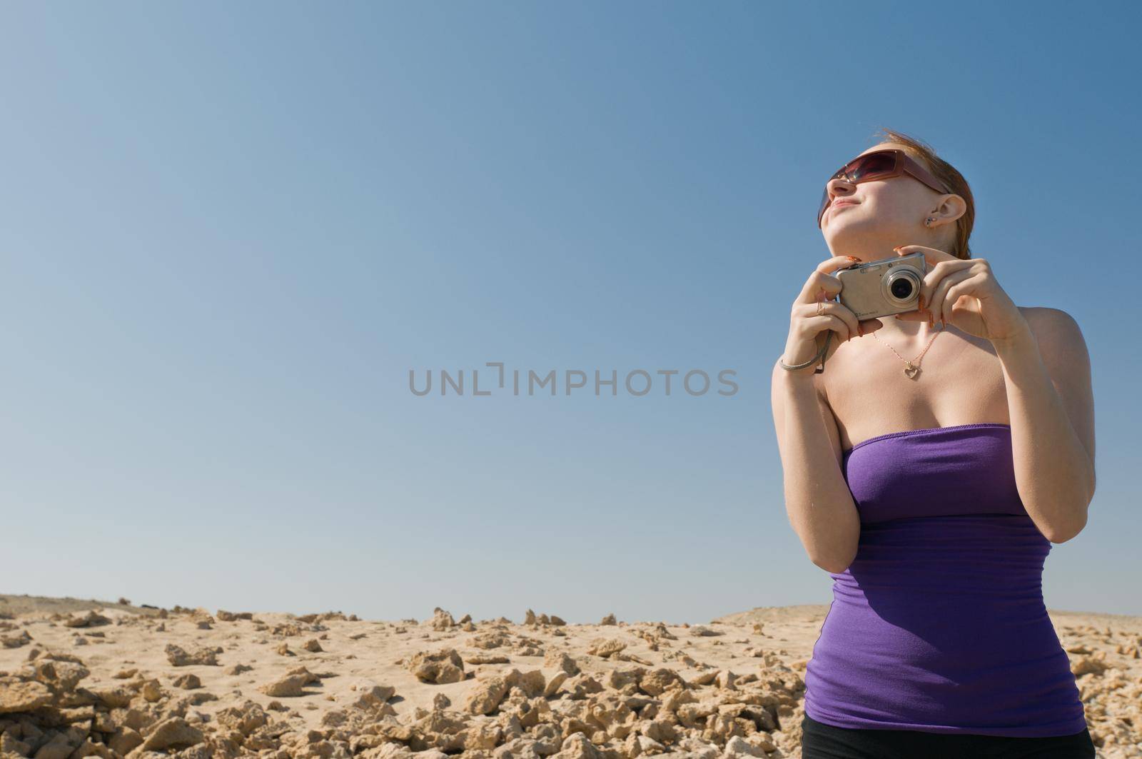 Girl with compact camera taking photos at the desert
