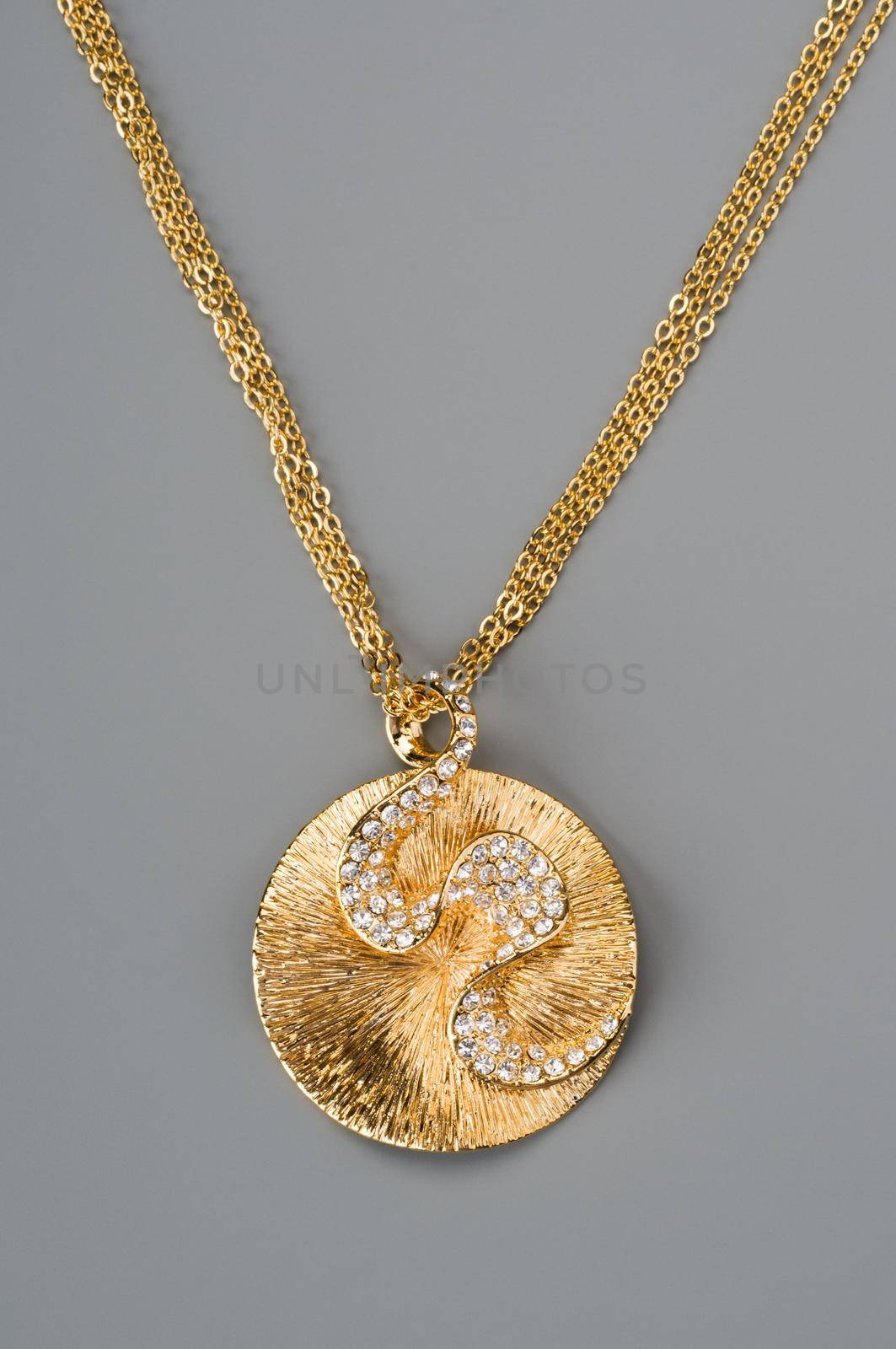 Gold necklace with pendant shot on gray background