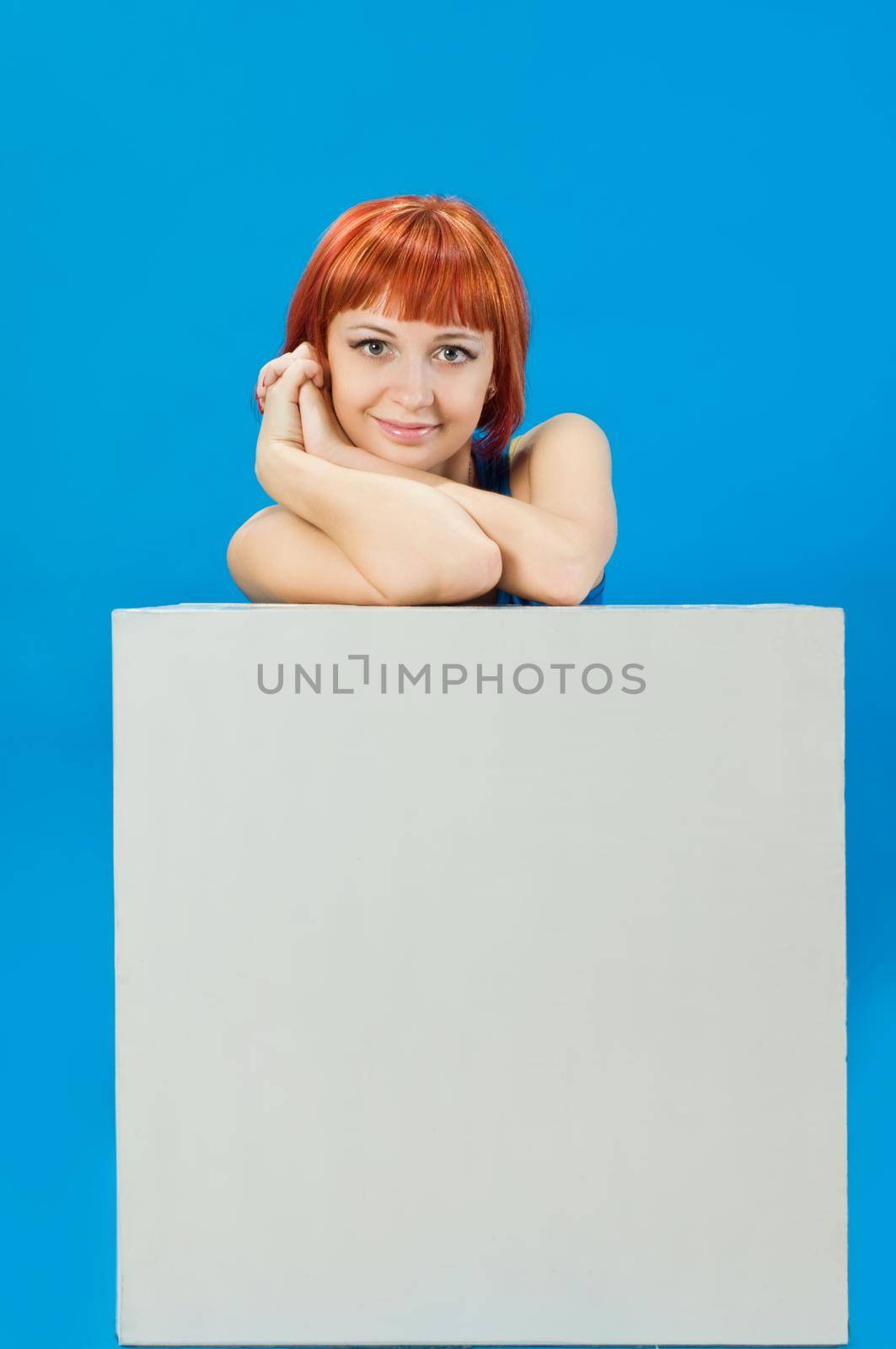 Beautiful red girl sitting behind blank board ready for your text
